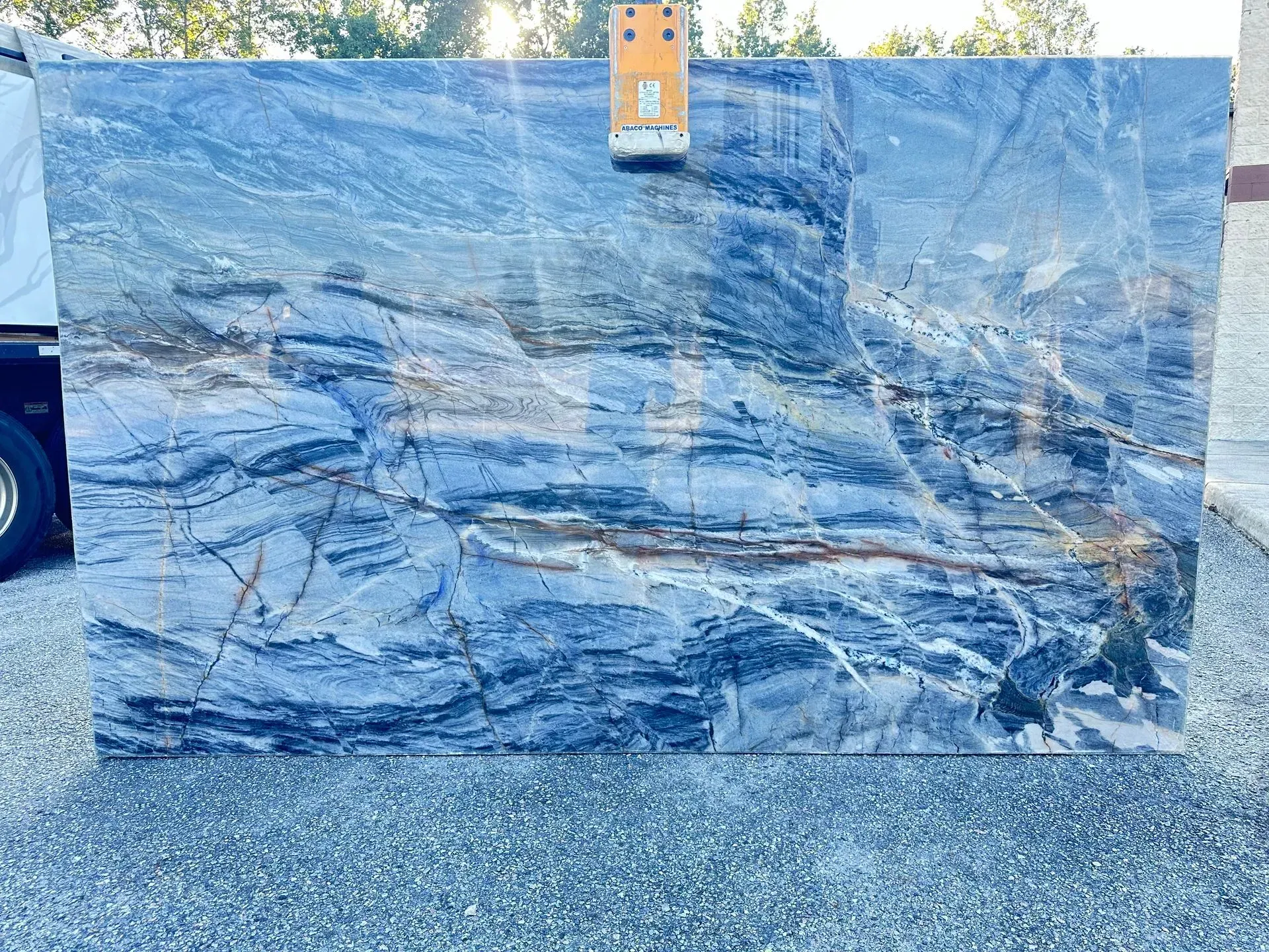 Large slab of blue and gray stone, with brown and gold veins, outdoors.