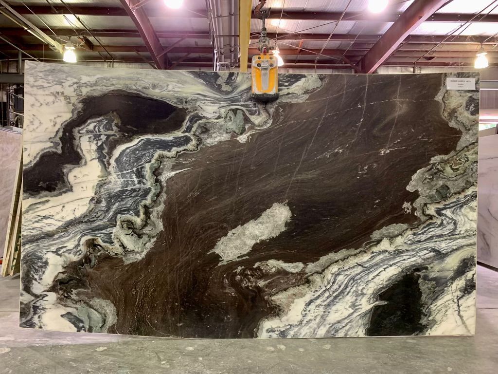 Large slab of dark brown and white marble with swirling patterns, indoors.