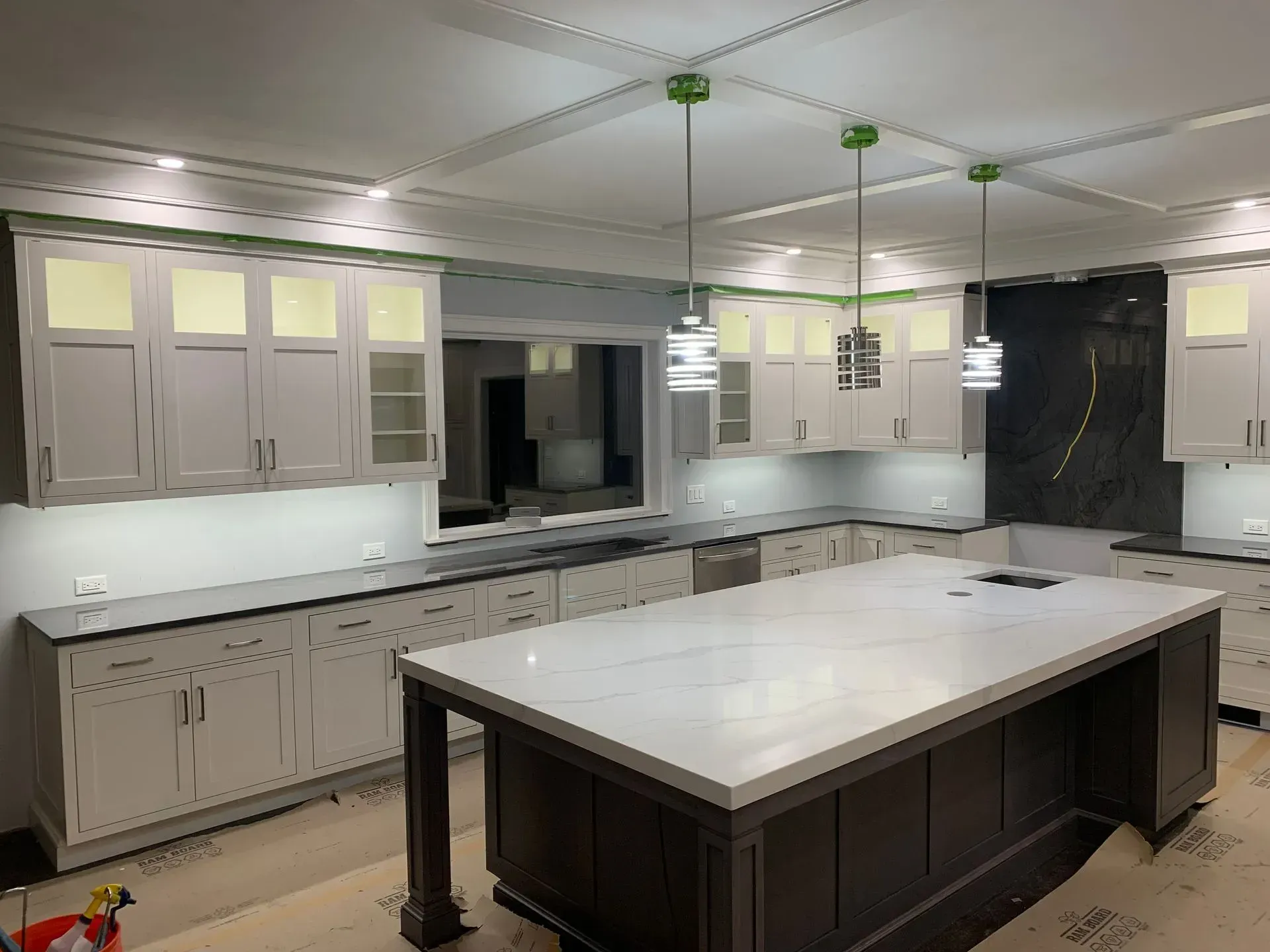 Newly remodeled kitchen with white cabinets, dark island, and pendant lights.
