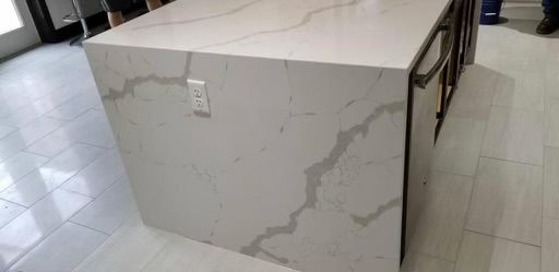 A white kitchen island with gray veining and an electrical outlet.