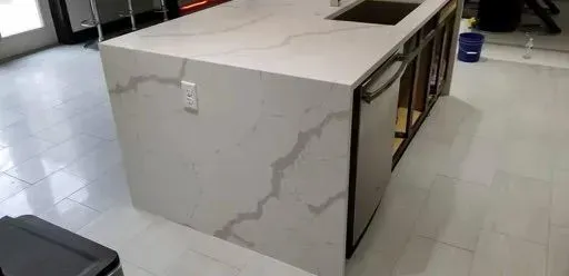 White kitchen island with veined countertop, built-in sink and unfinished cabinets.