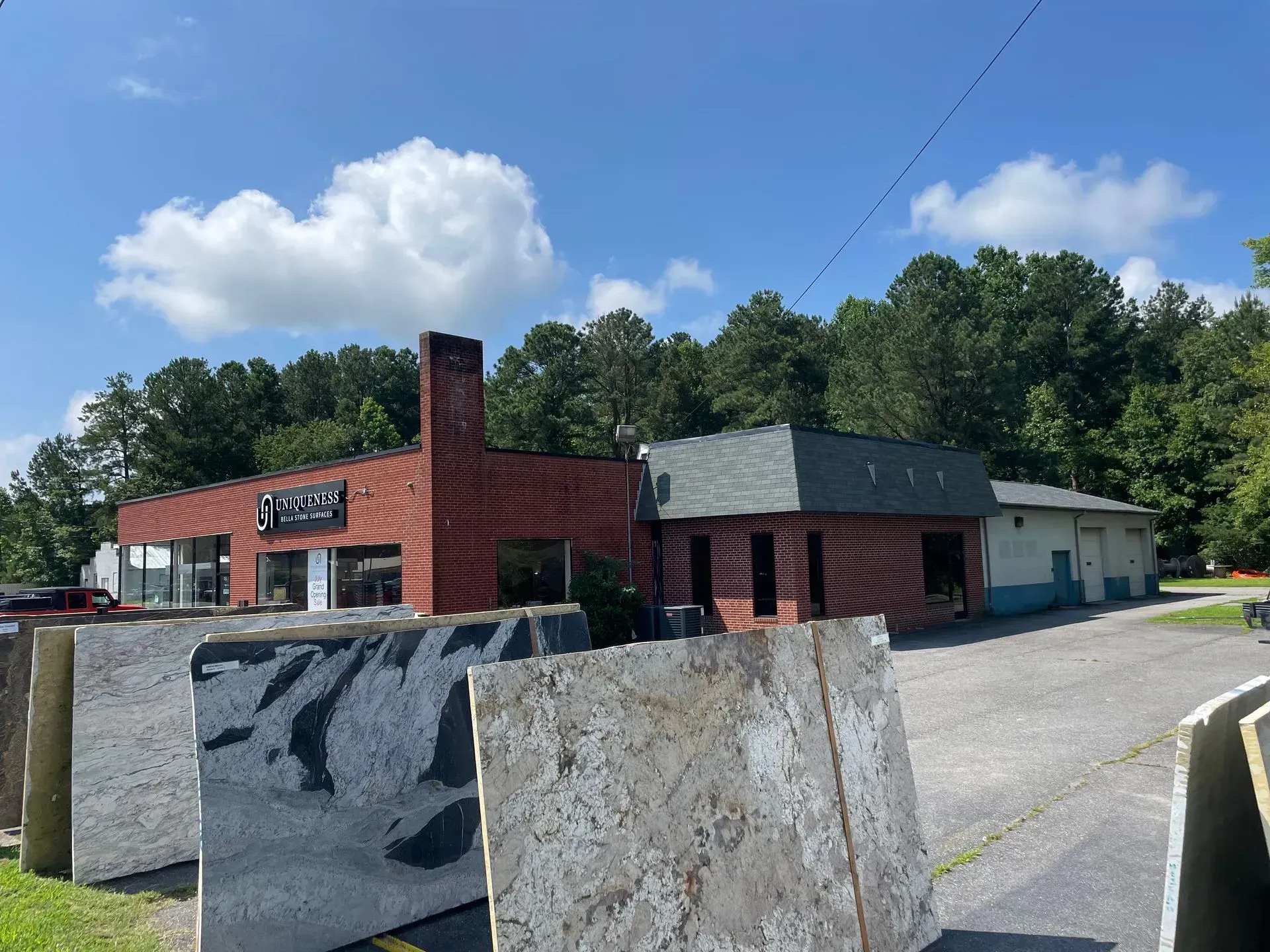 Exterior of a brick building with granite slabs in the foreground, under a partly cloudy sky.