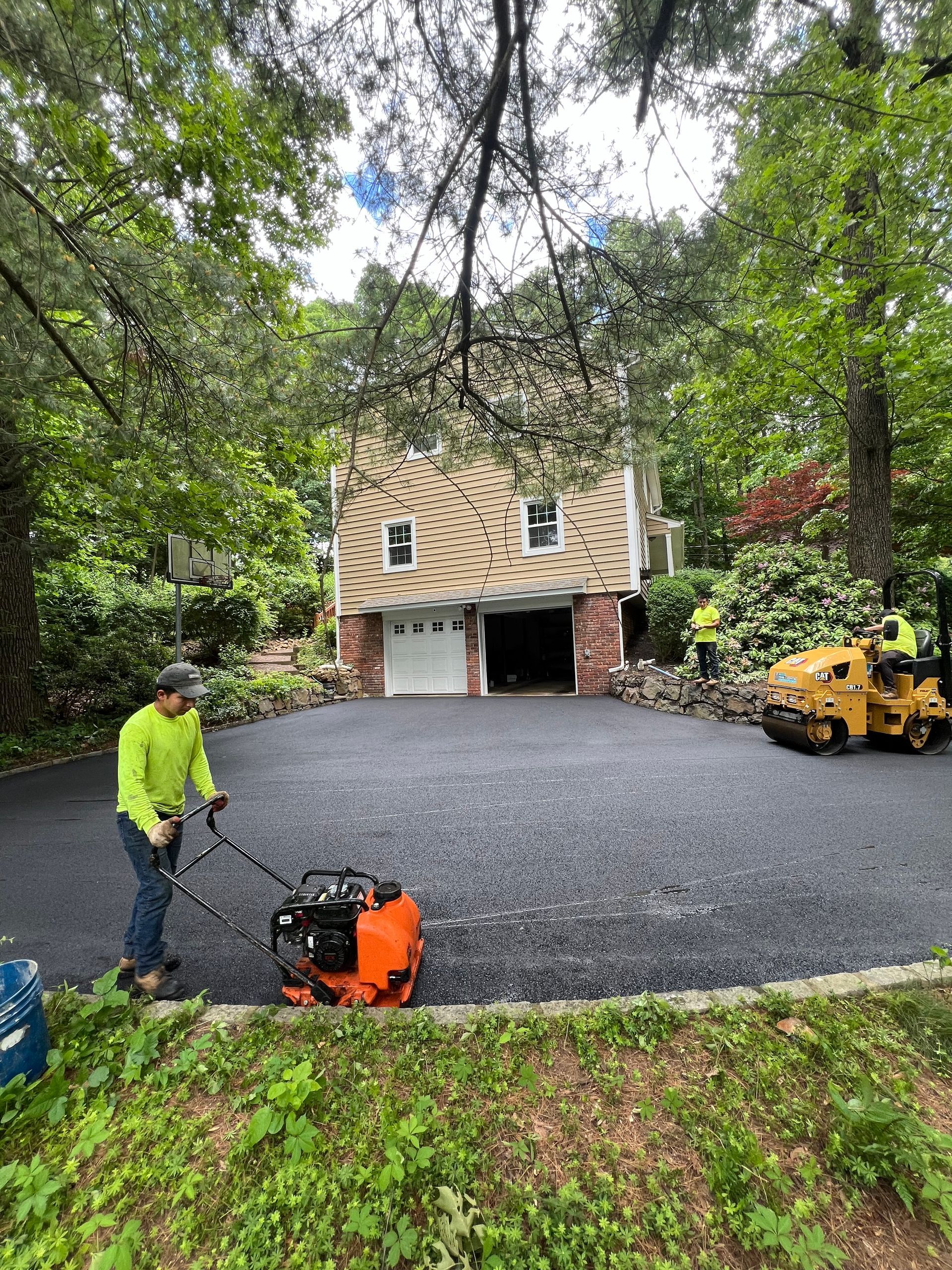 A man is paving a driveway in front of a house.