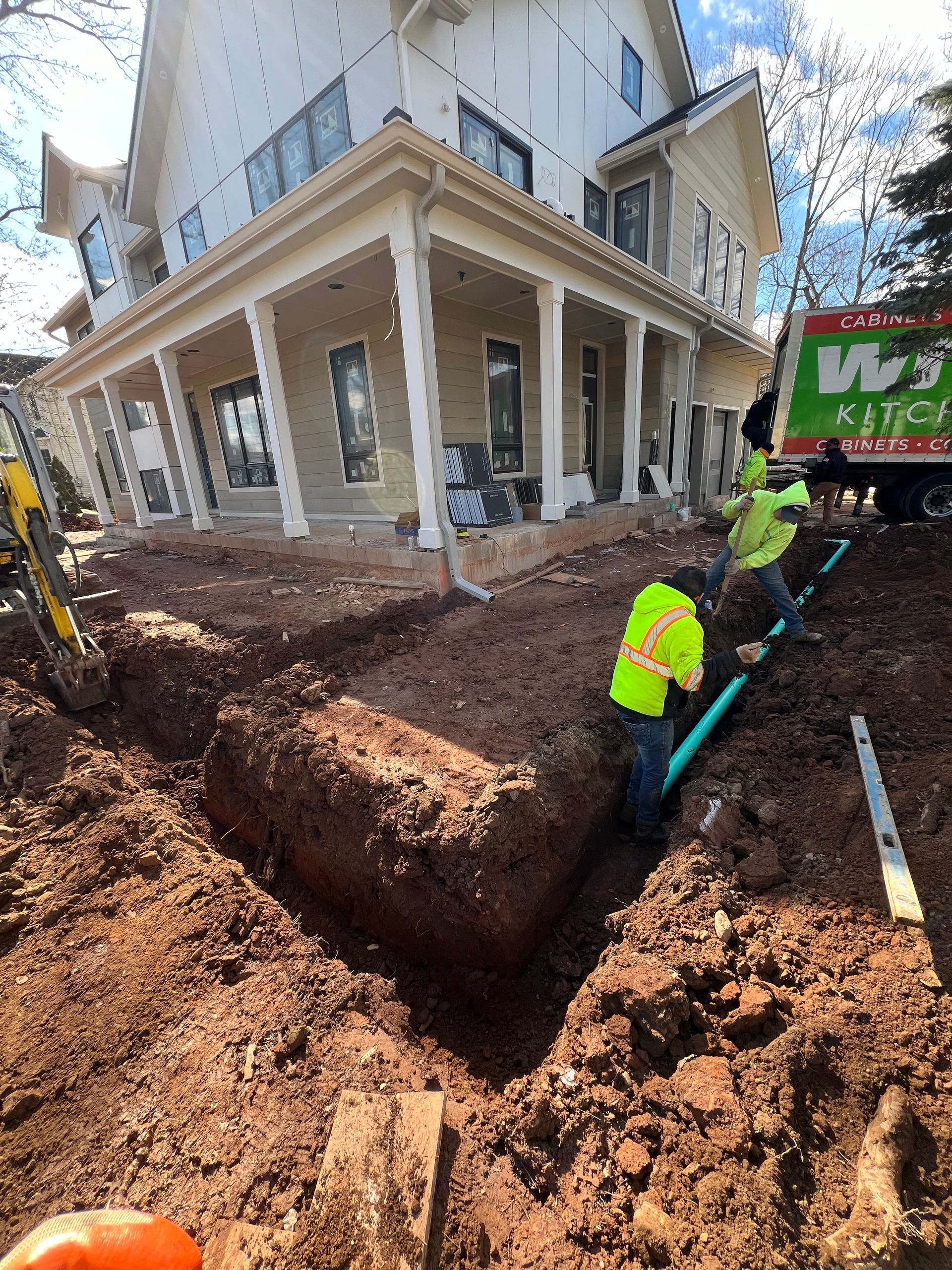 A man is digging a hole in the dirt in front of a house.