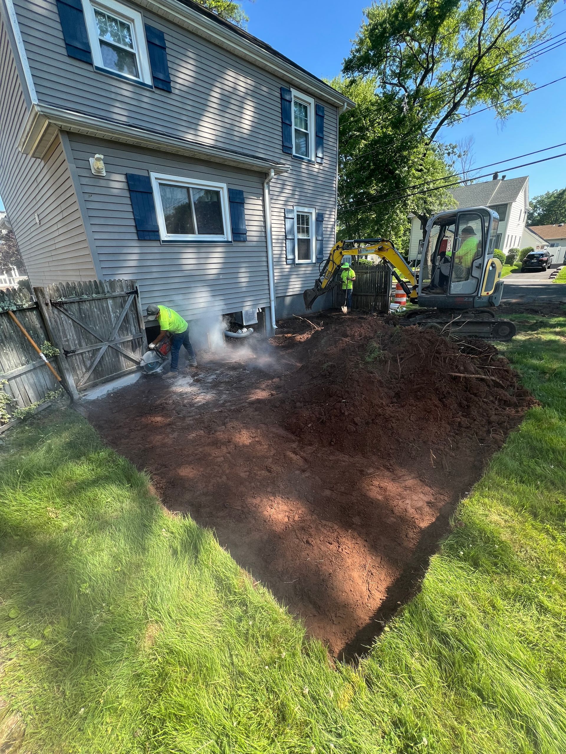 A man is digging a hole in the ground in front of a house.