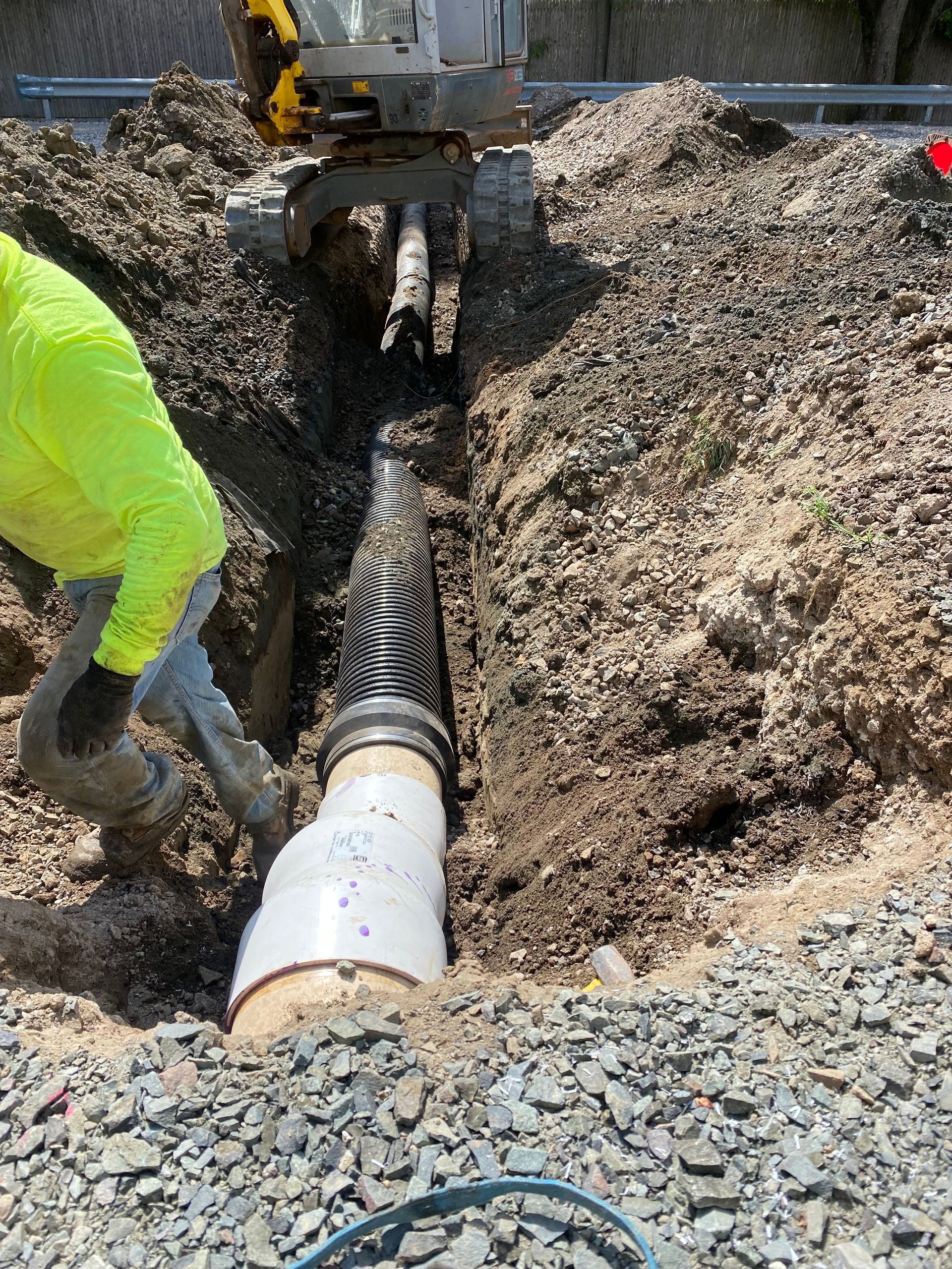 A man is digging a hole in the ground to install a pipe.