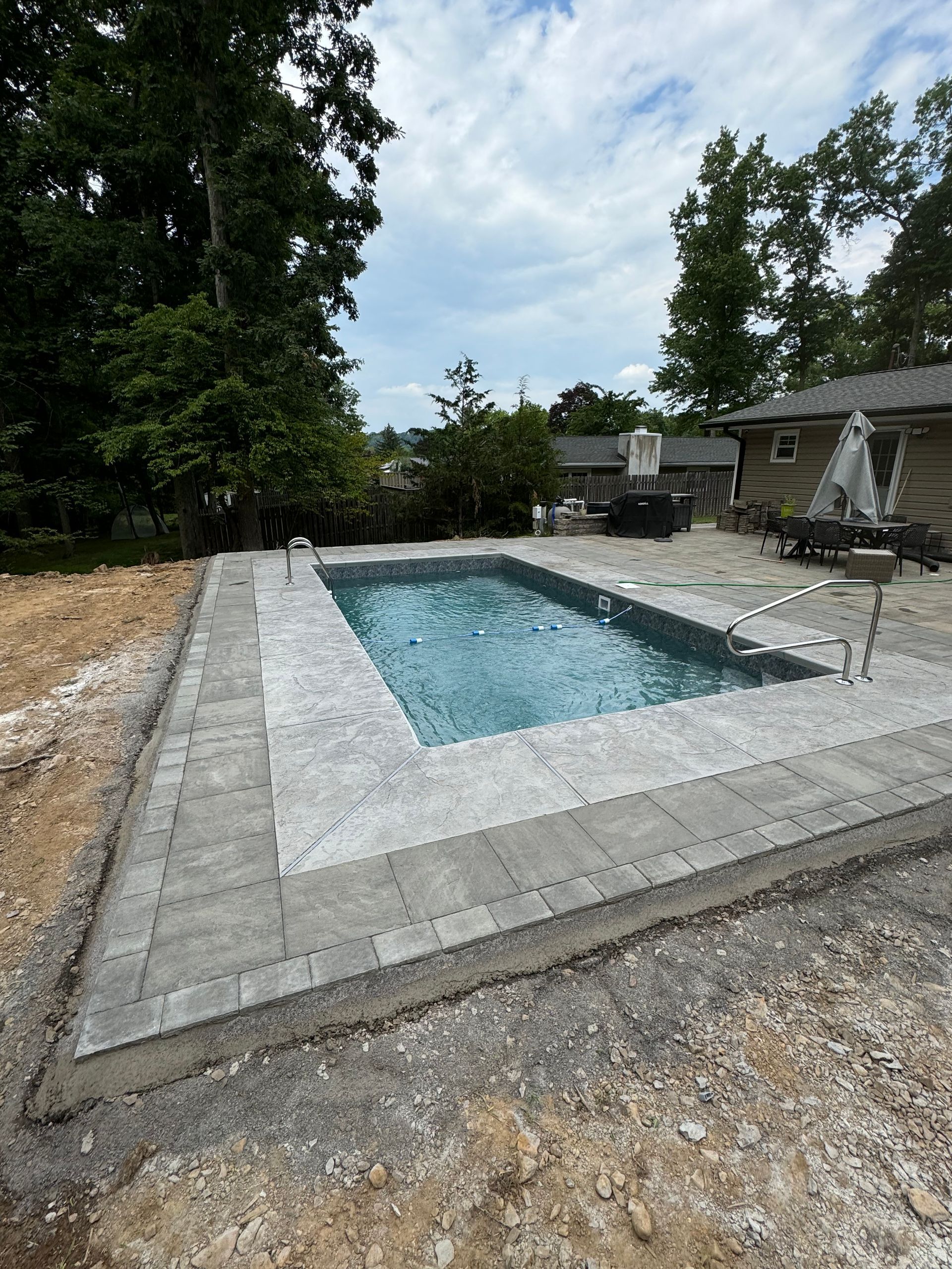 A large swimming pool is surrounded by a brick patio.