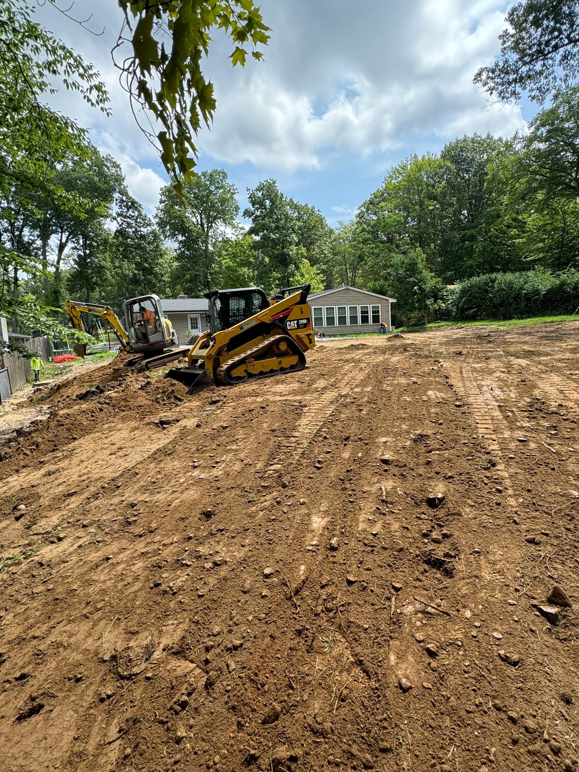 A bulldozer is working on a dirt field in front of a house.