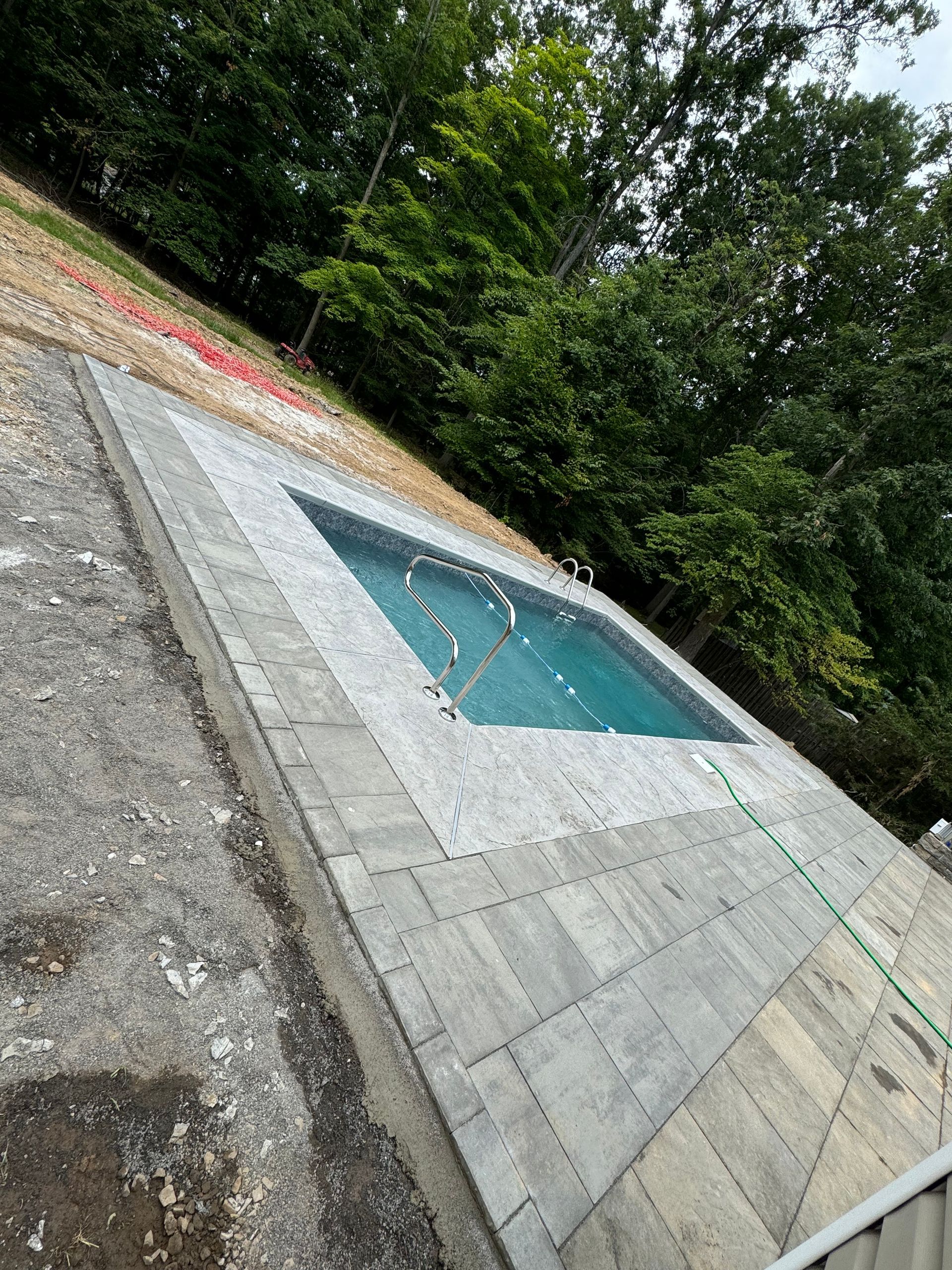 A large swimming pool is sitting on top of a brick patio.