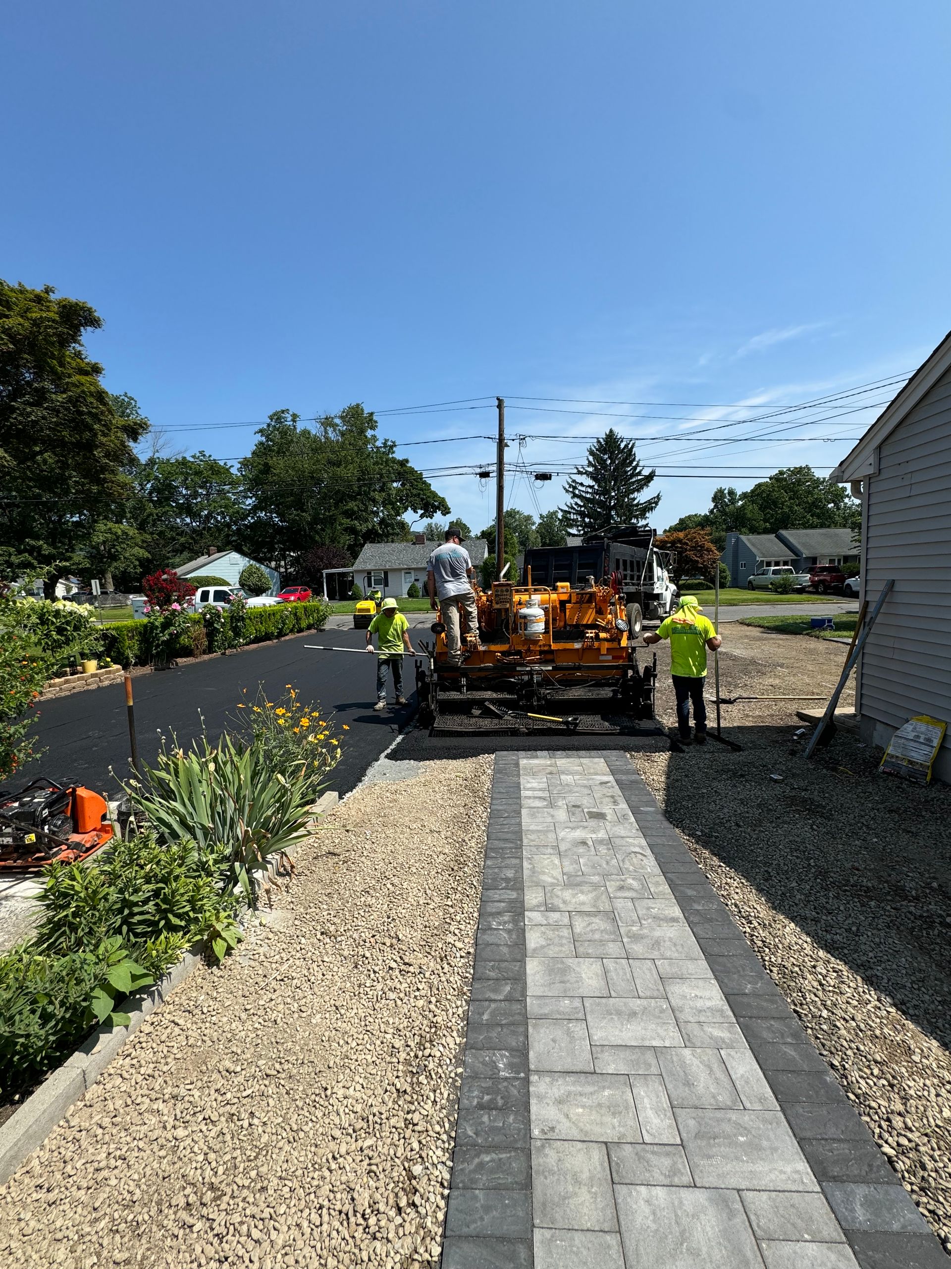 A group of construction workers are working on a driveway.
