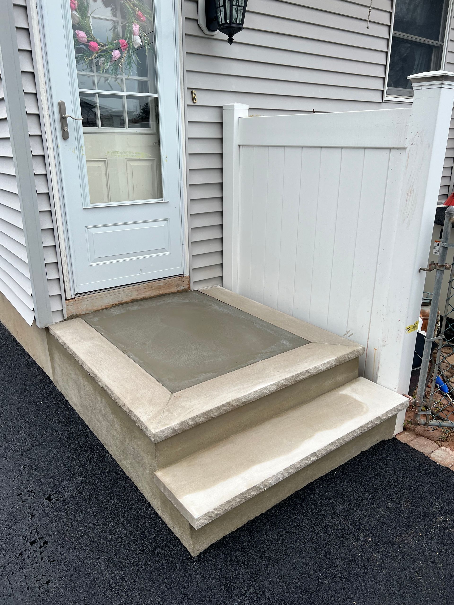 A white fence surrounds a porch with stairs and a door.
