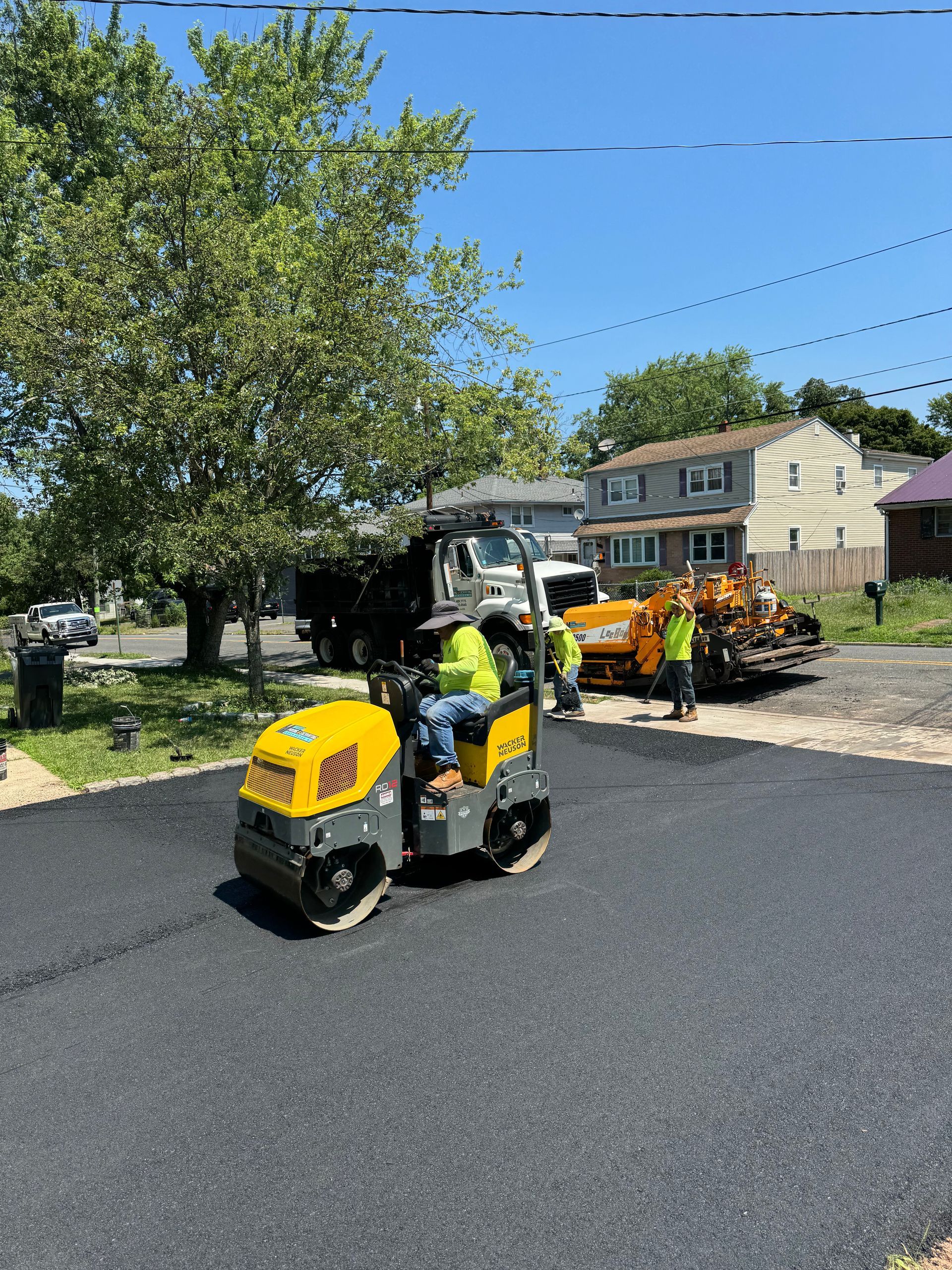 A man is driving a yellow roller on a road.