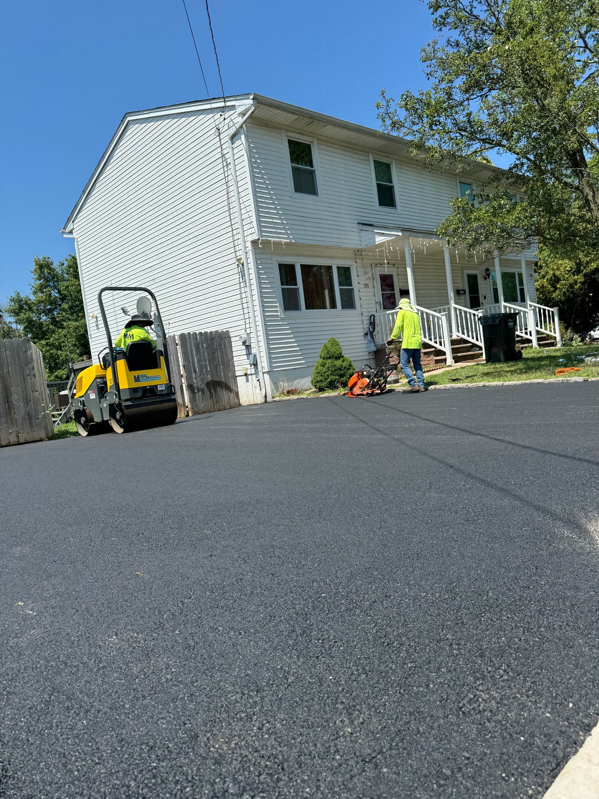 A man is walking down a road in front of a house.