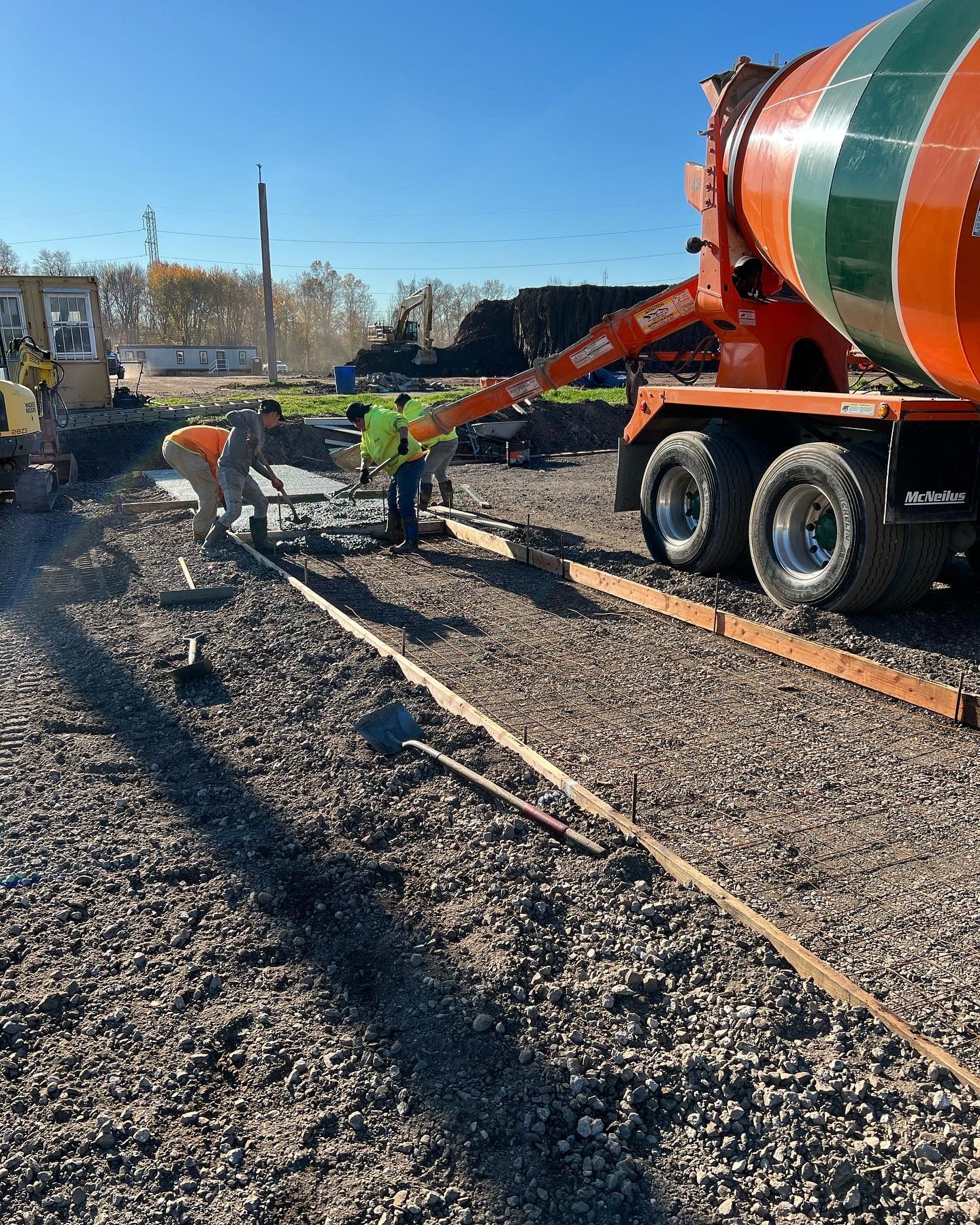 A concrete mixer is being used to pour concrete on a gravel road.