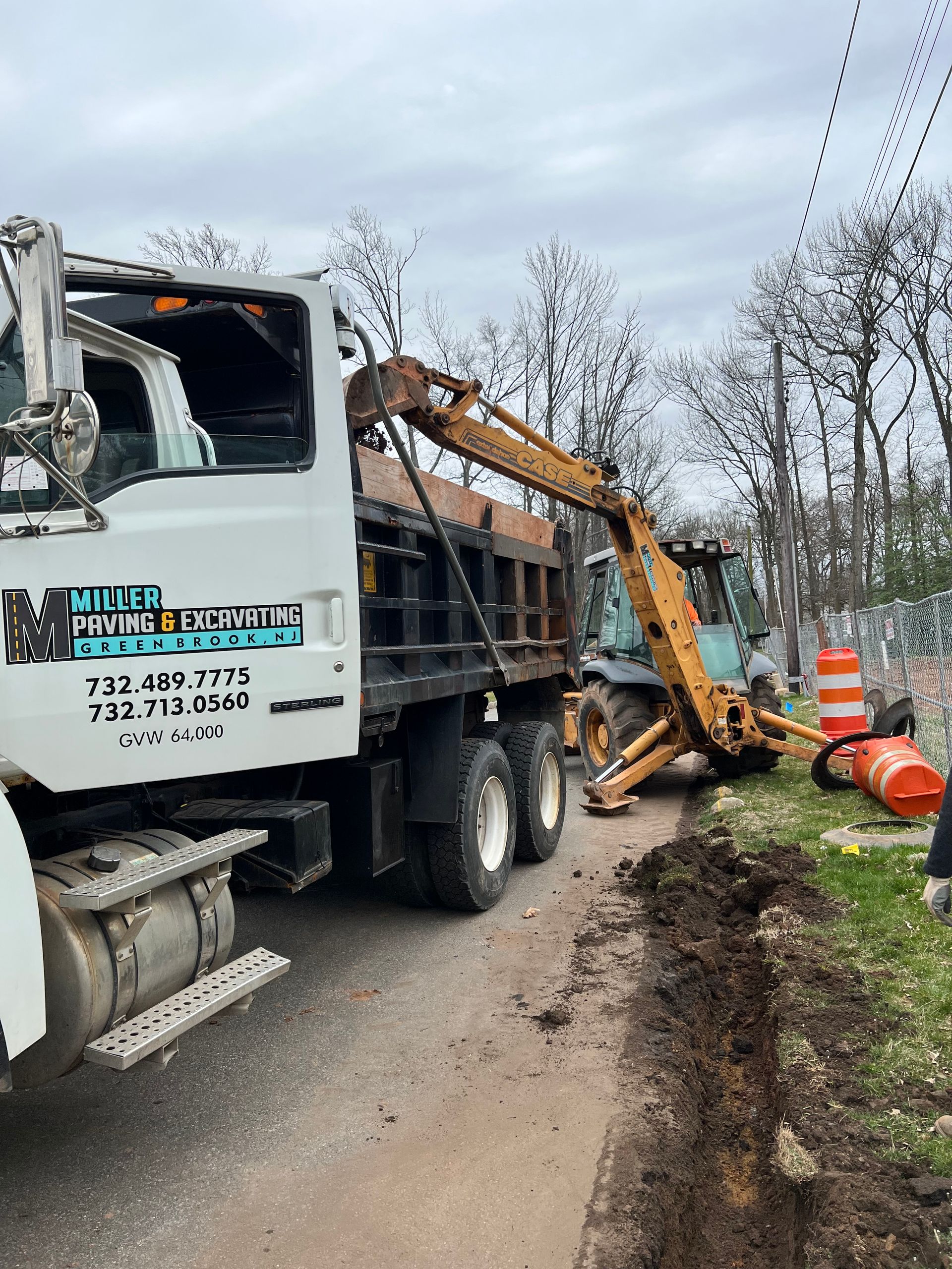 A dump truck is parked on the side of the road next to a construction vehicle.