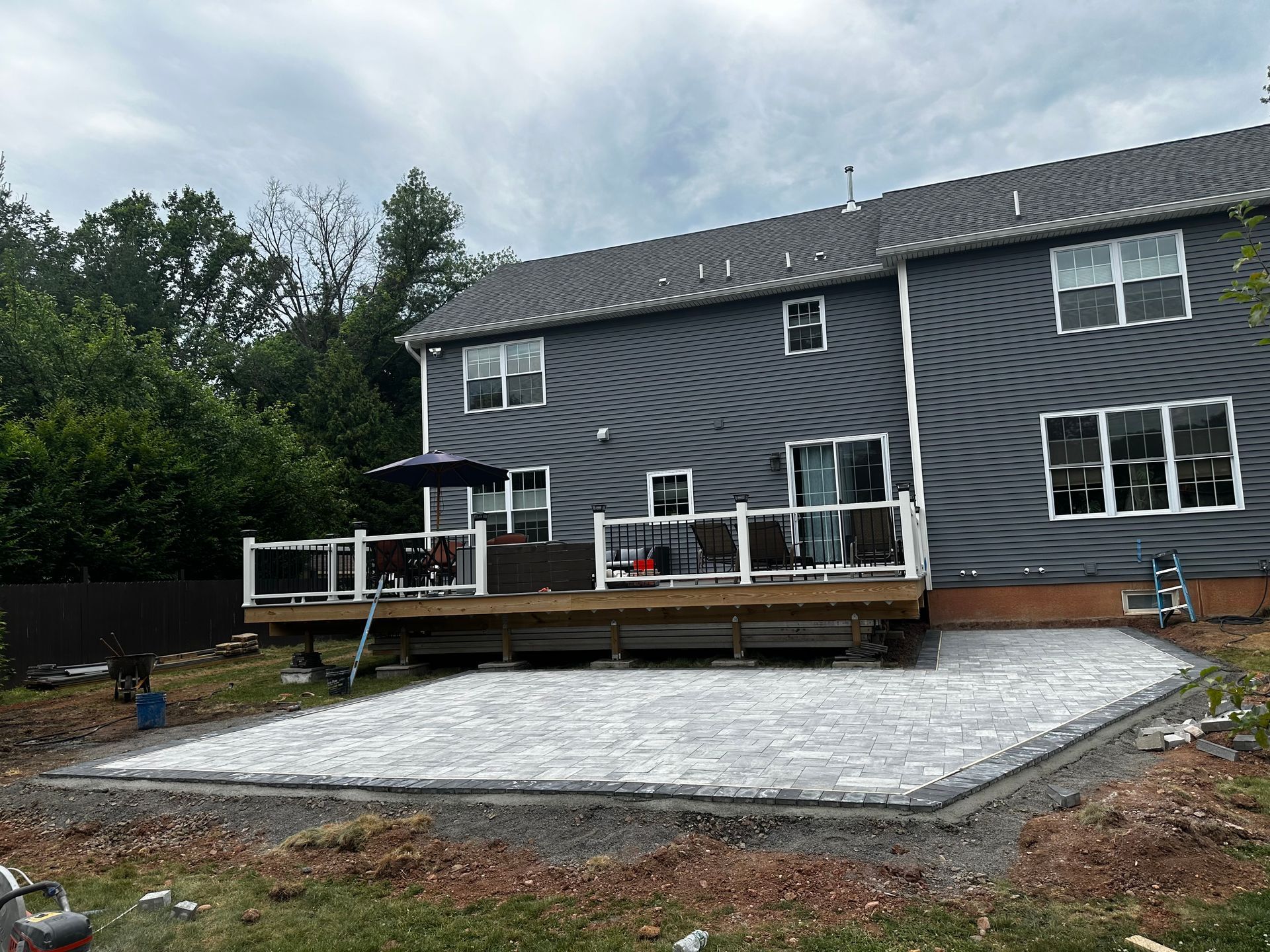 A large gray house with a large deck in the backyard.
