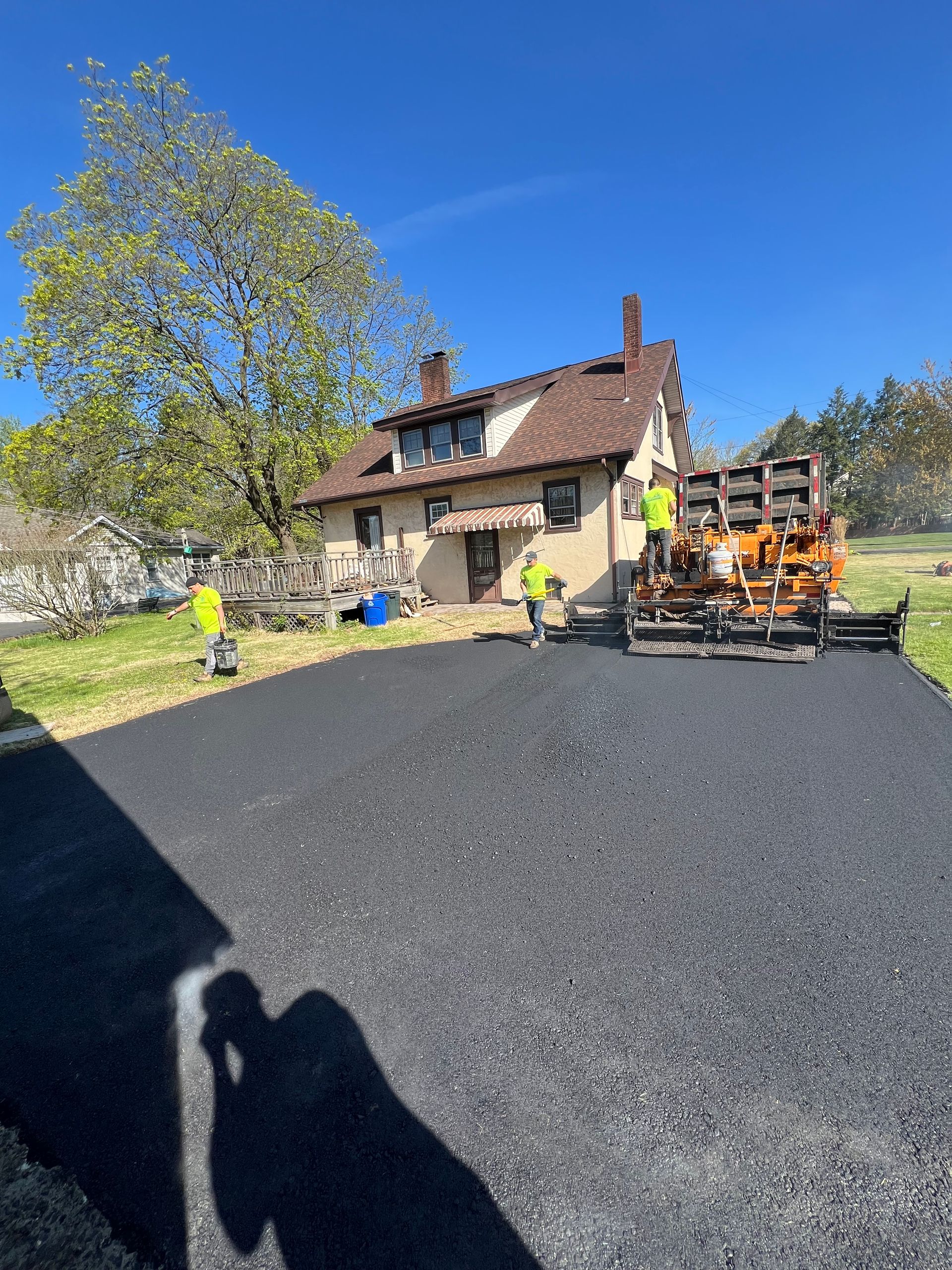 A group of people are working on a driveway in front of a house.