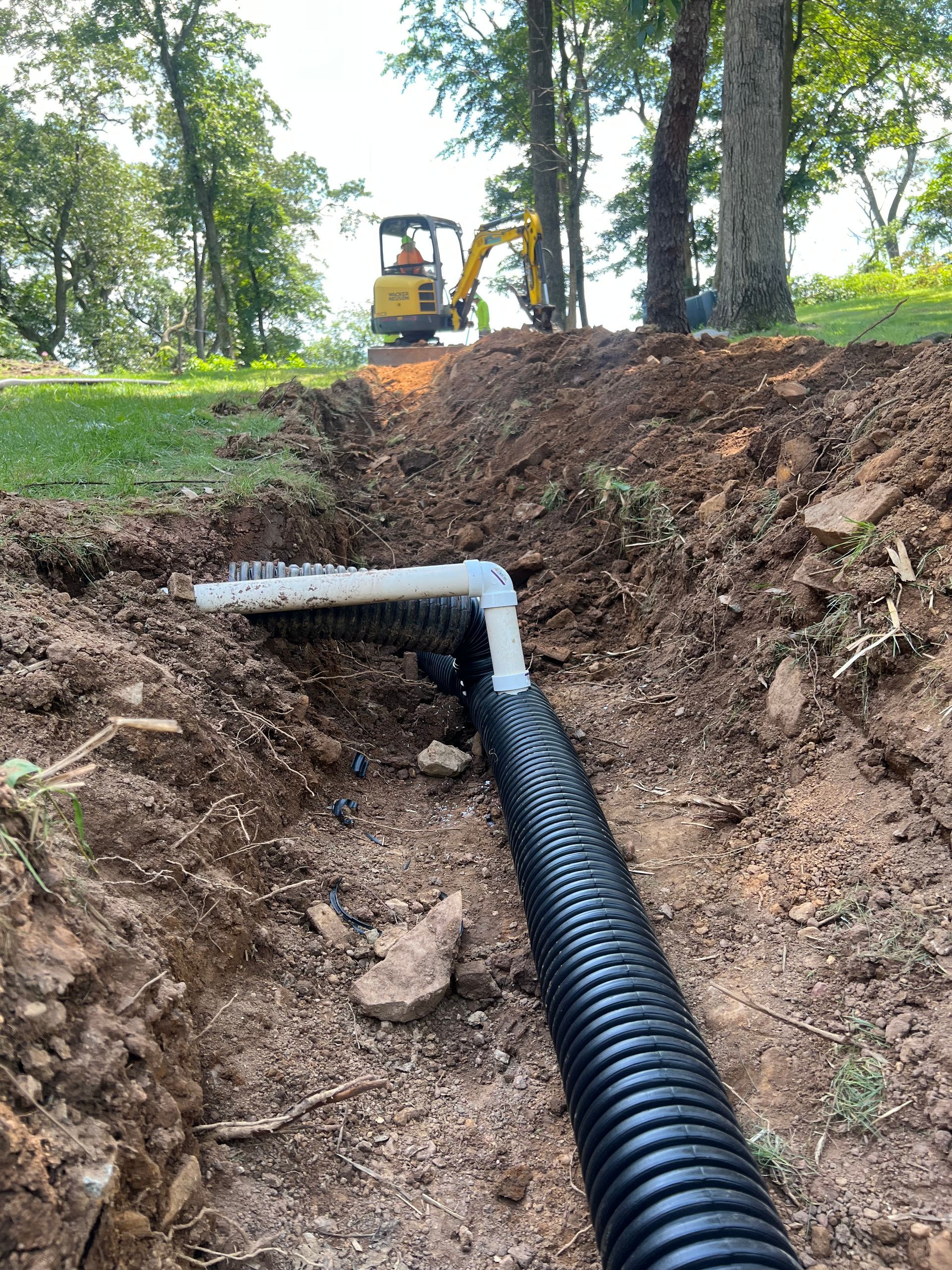 A drain pipe is being installed in a hole in the ground.