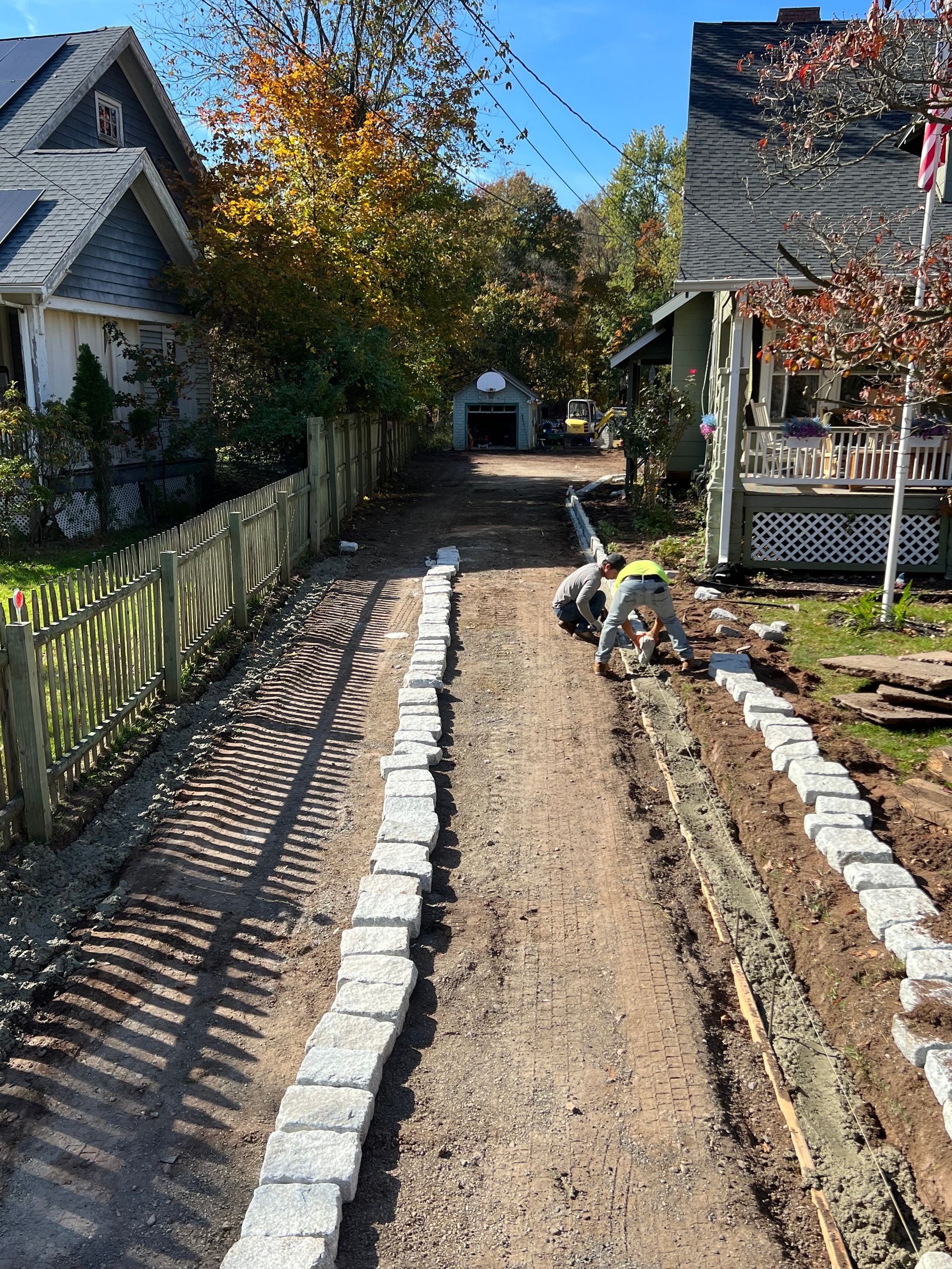 A man is working on a driveway next to a house.