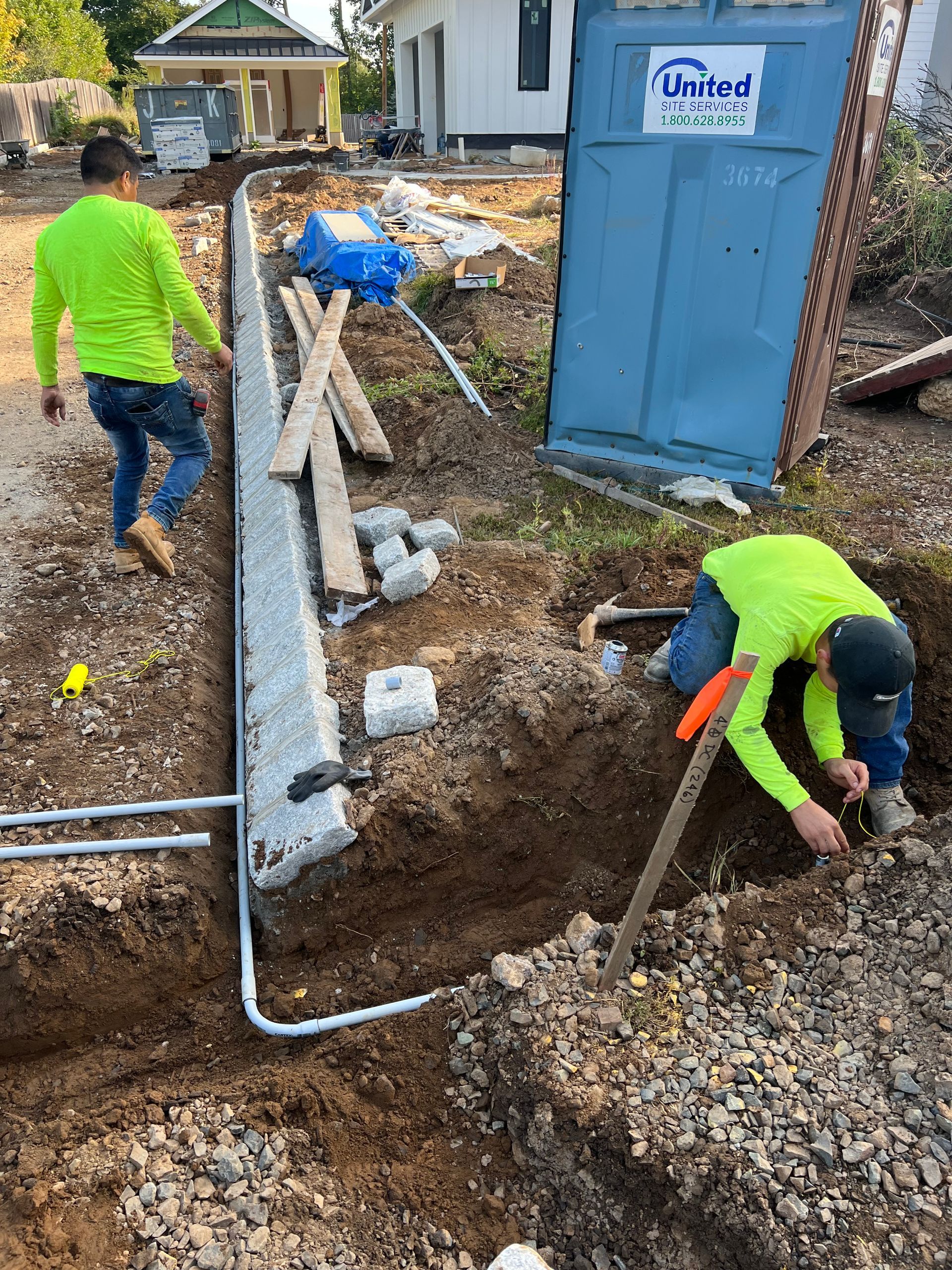 Two construction workers are working in the dirt on a construction site.