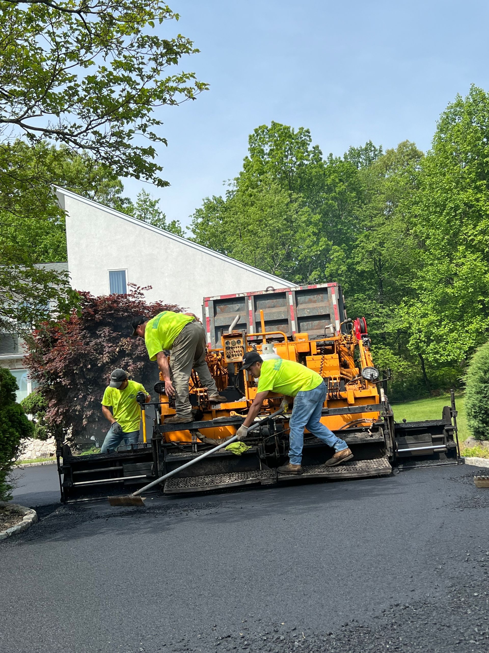 A group of construction workers are working on a driveway.