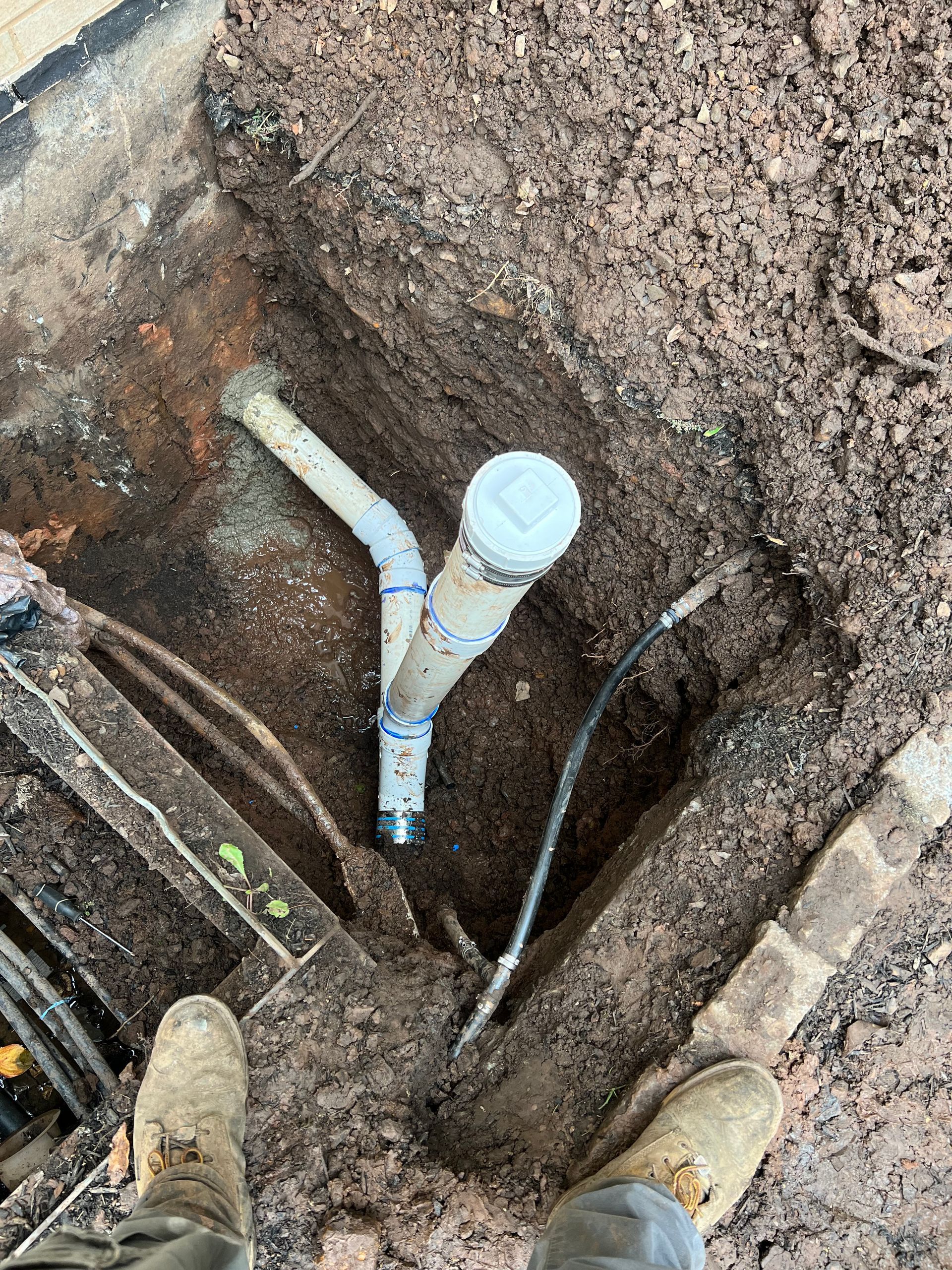 A person is standing next to a pipe in the dirt.
