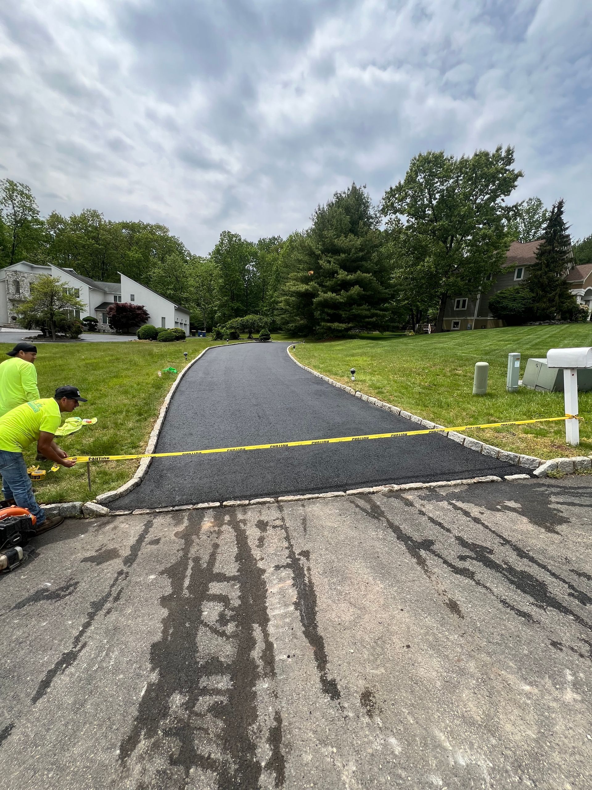 A group of men are working on a paved driveway.