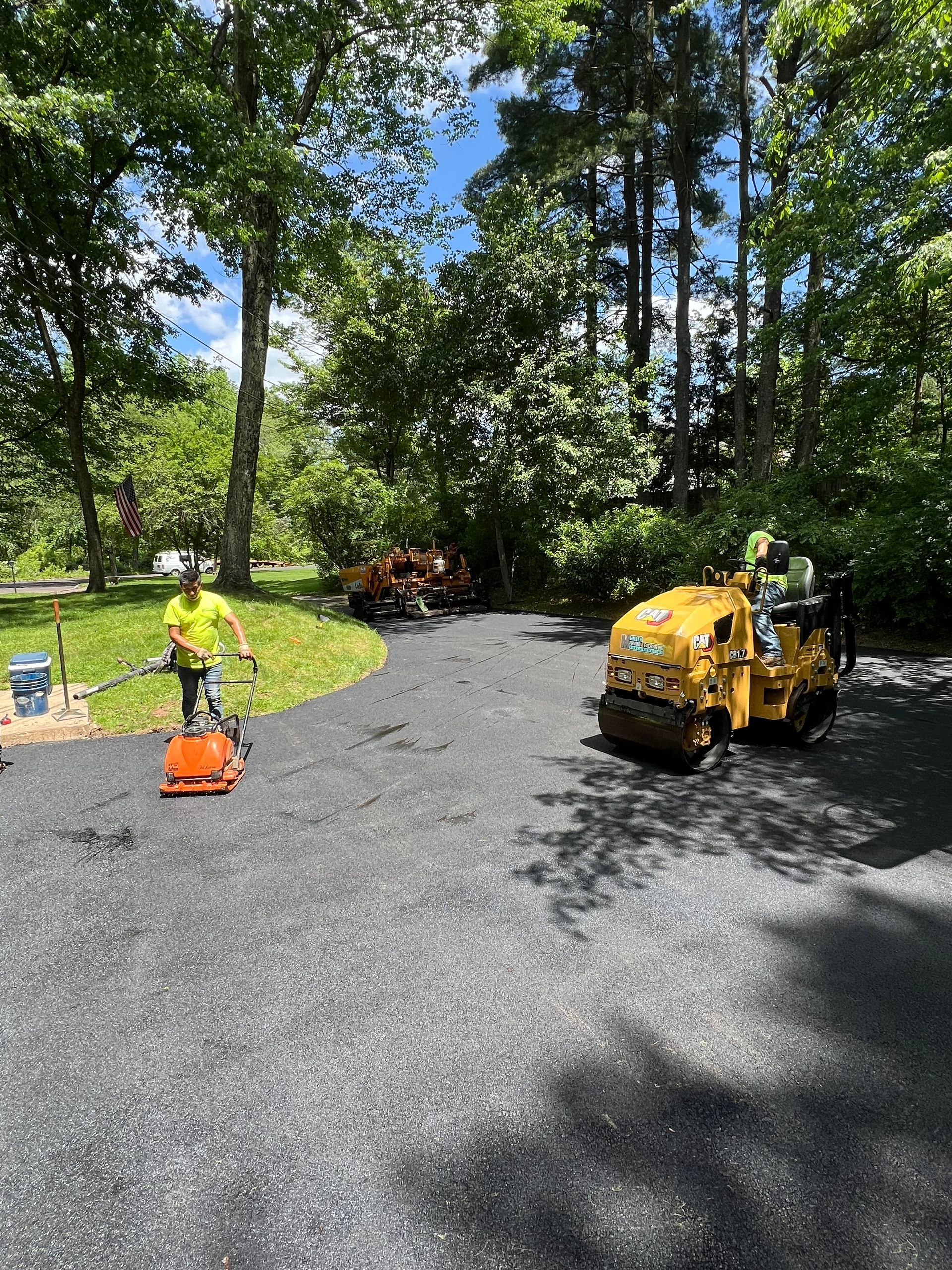A man is standing next to a yellow truck in a driveway.
