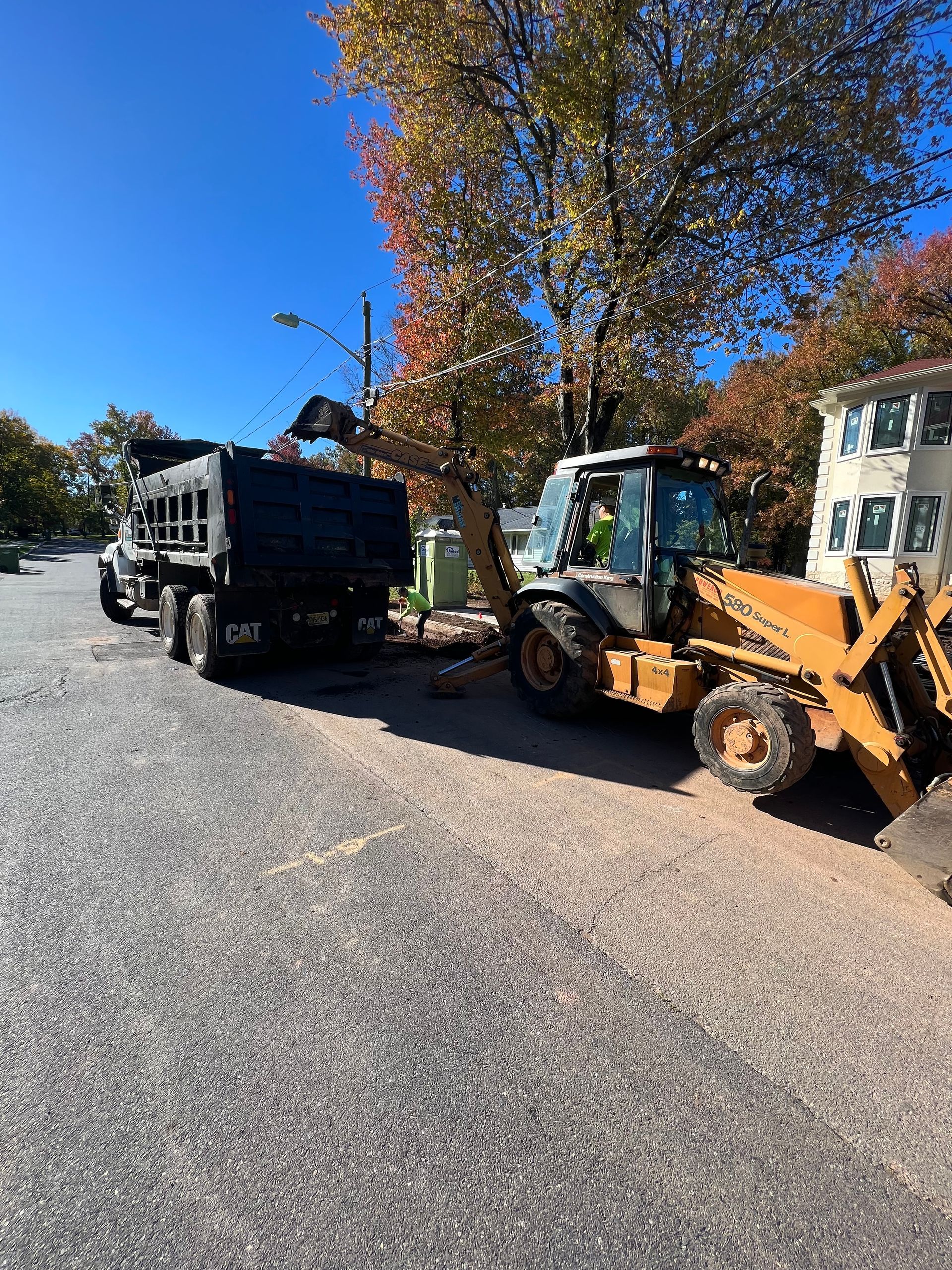 A dump truck and a bulldozer are parked on the side of the road.