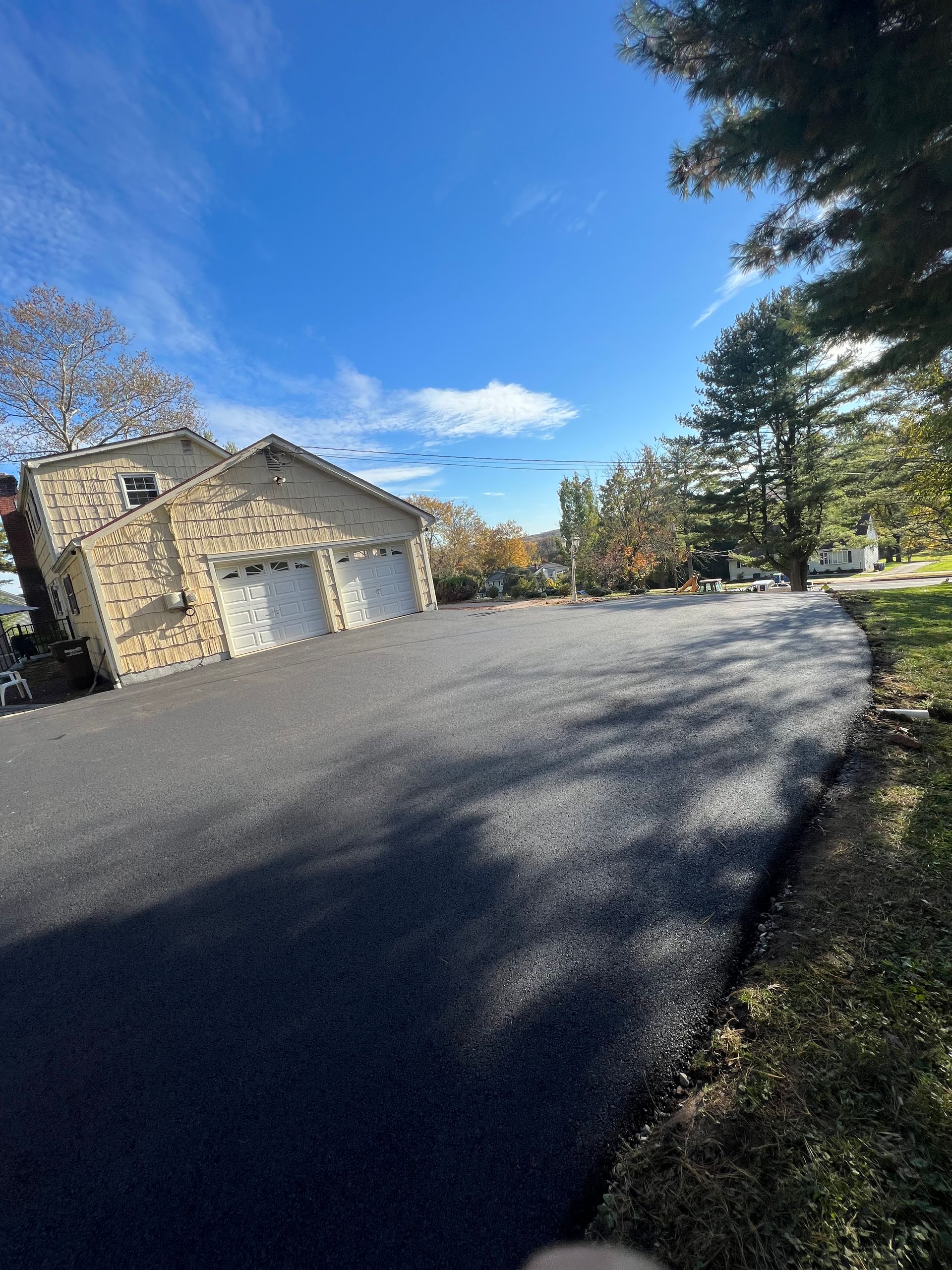 A driveway leading to a garage with a stone building in the background.