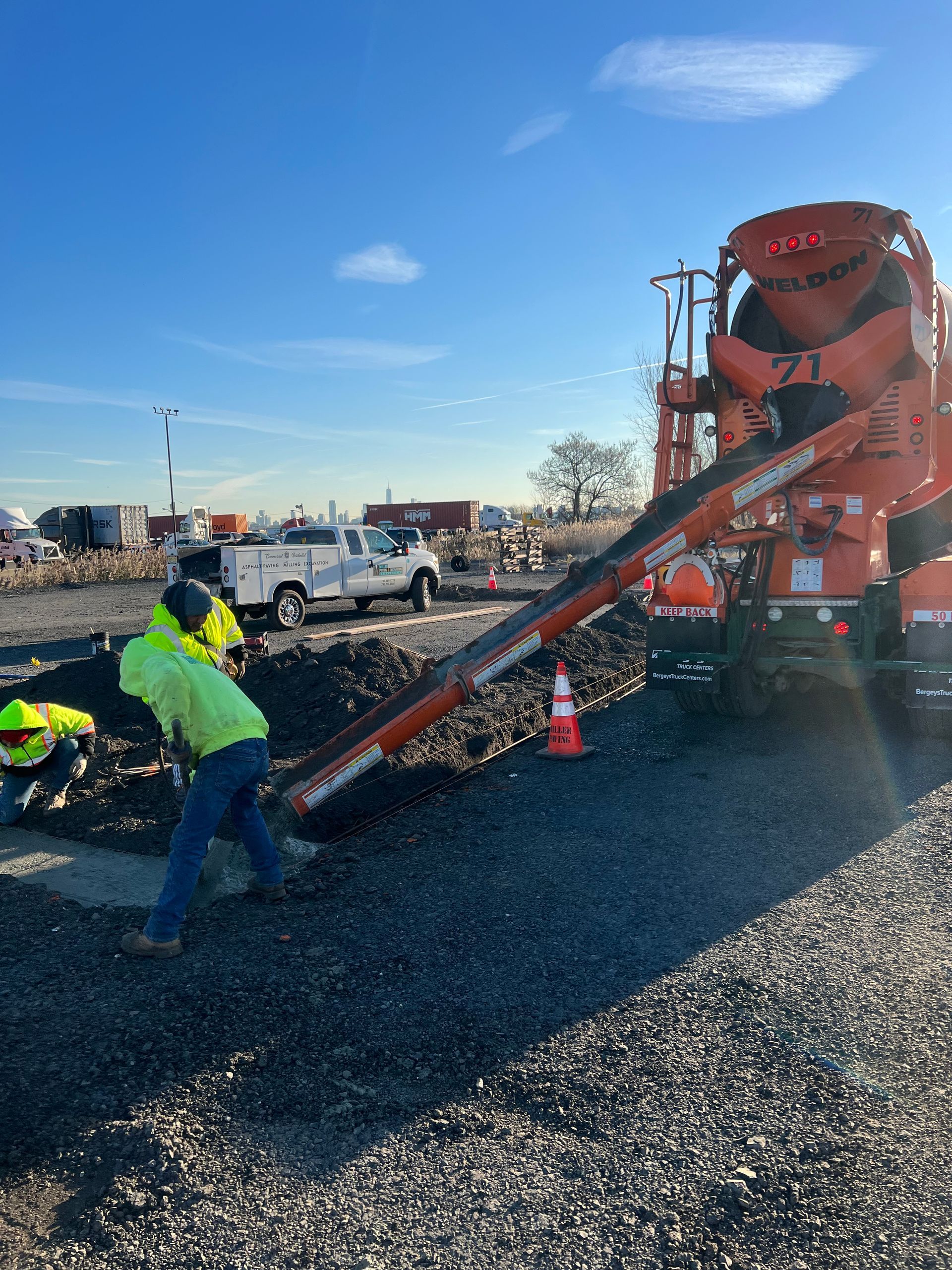 A concrete mixer is pouring concrete into a gravel area.