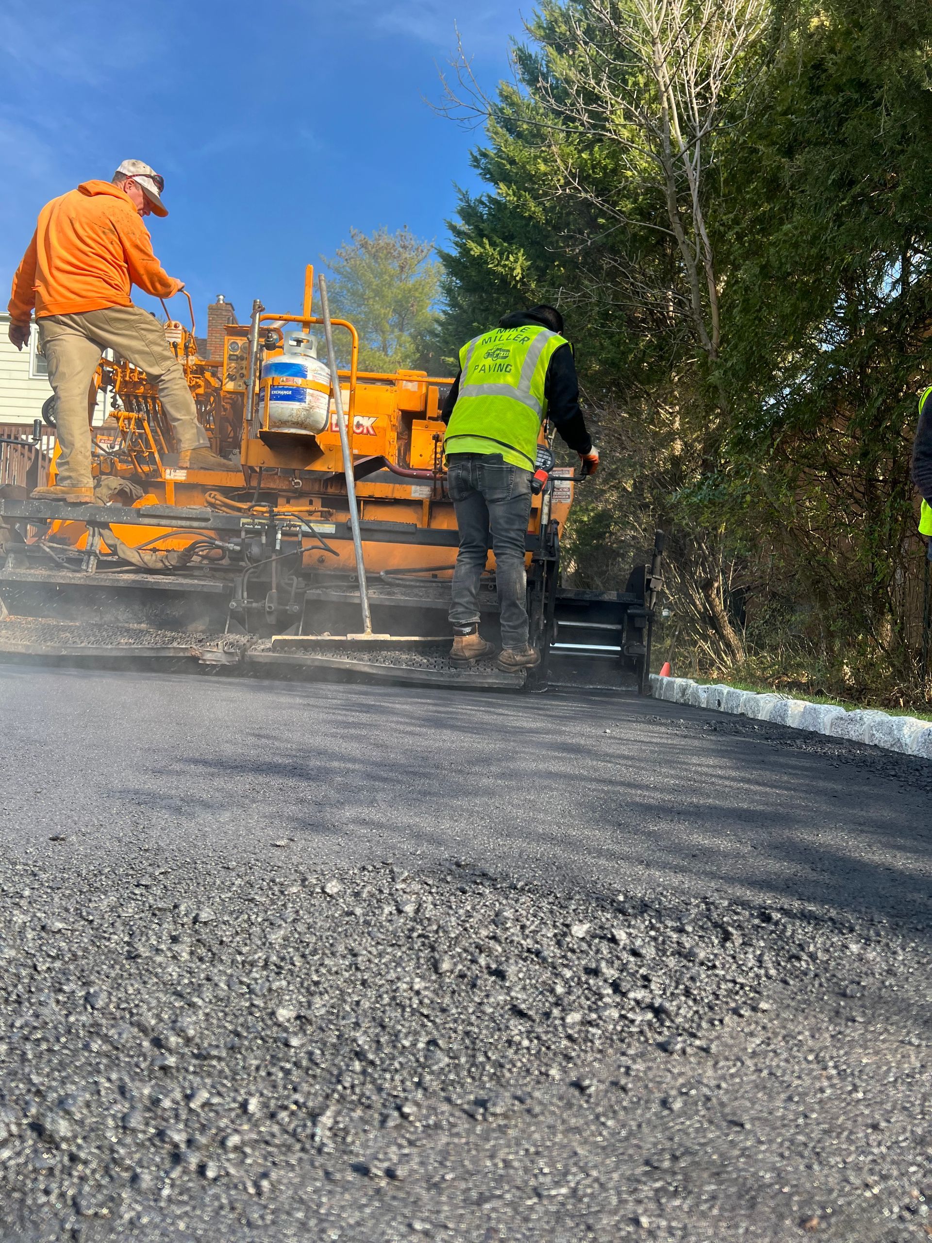 A group of construction workers are laying asphalt on a road.