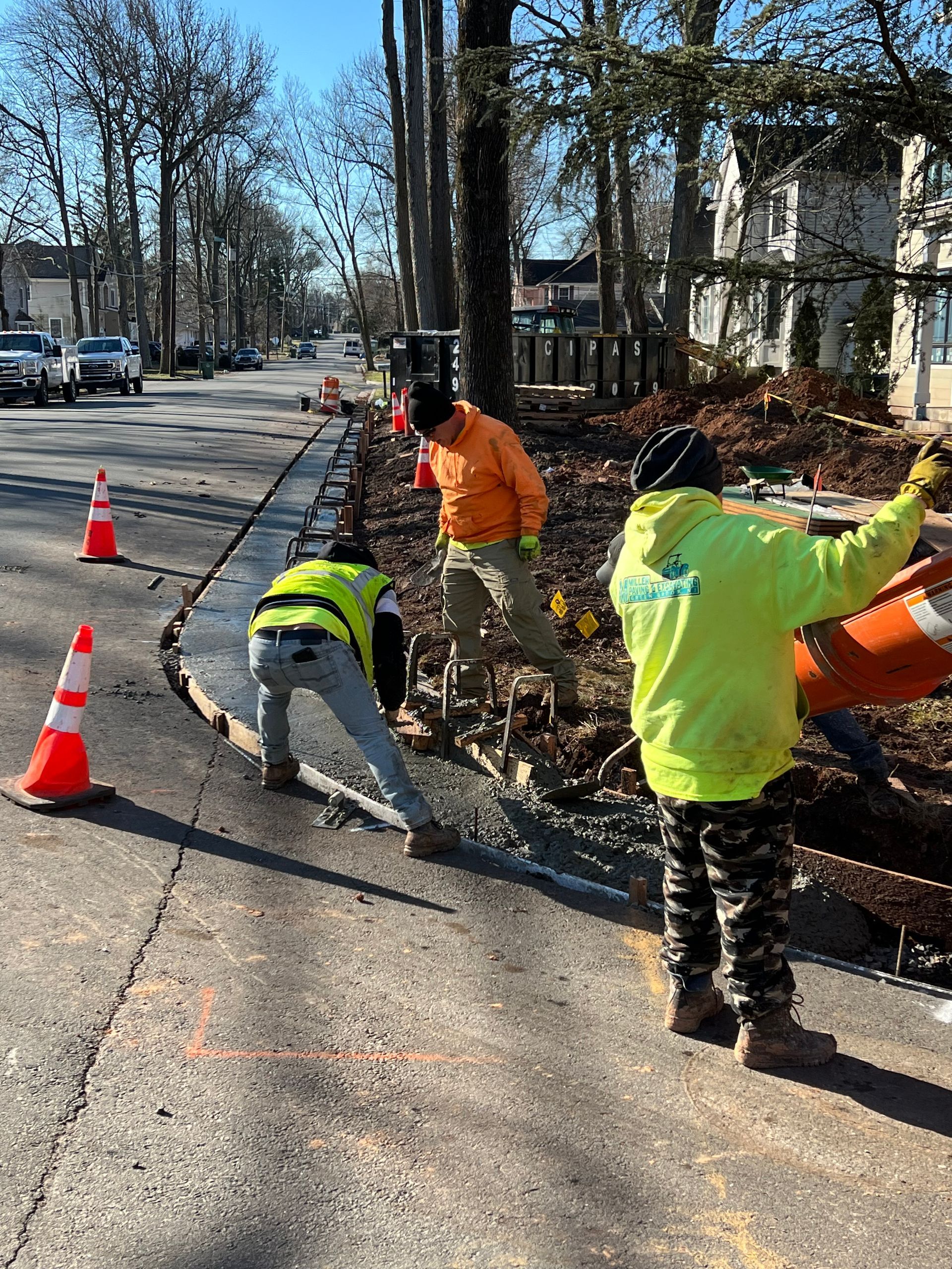 A group of construction workers are working on the side of a road.