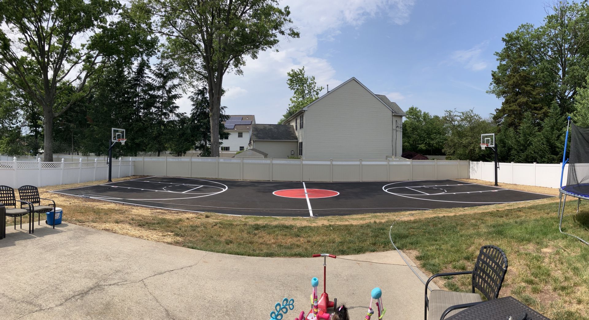 There is a basketball court in the backyard of a house.