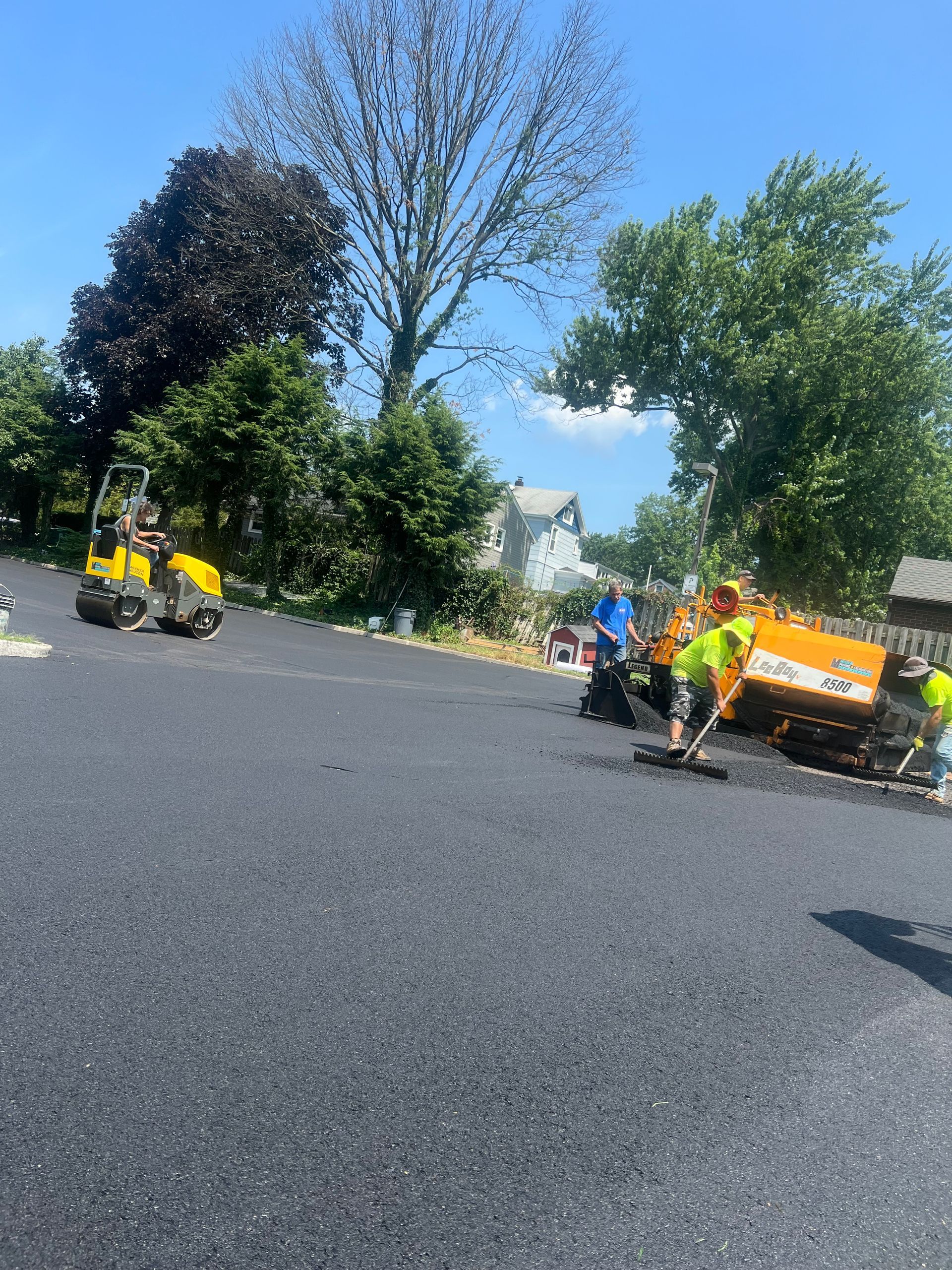 A group of people are laying asphalt on a road.