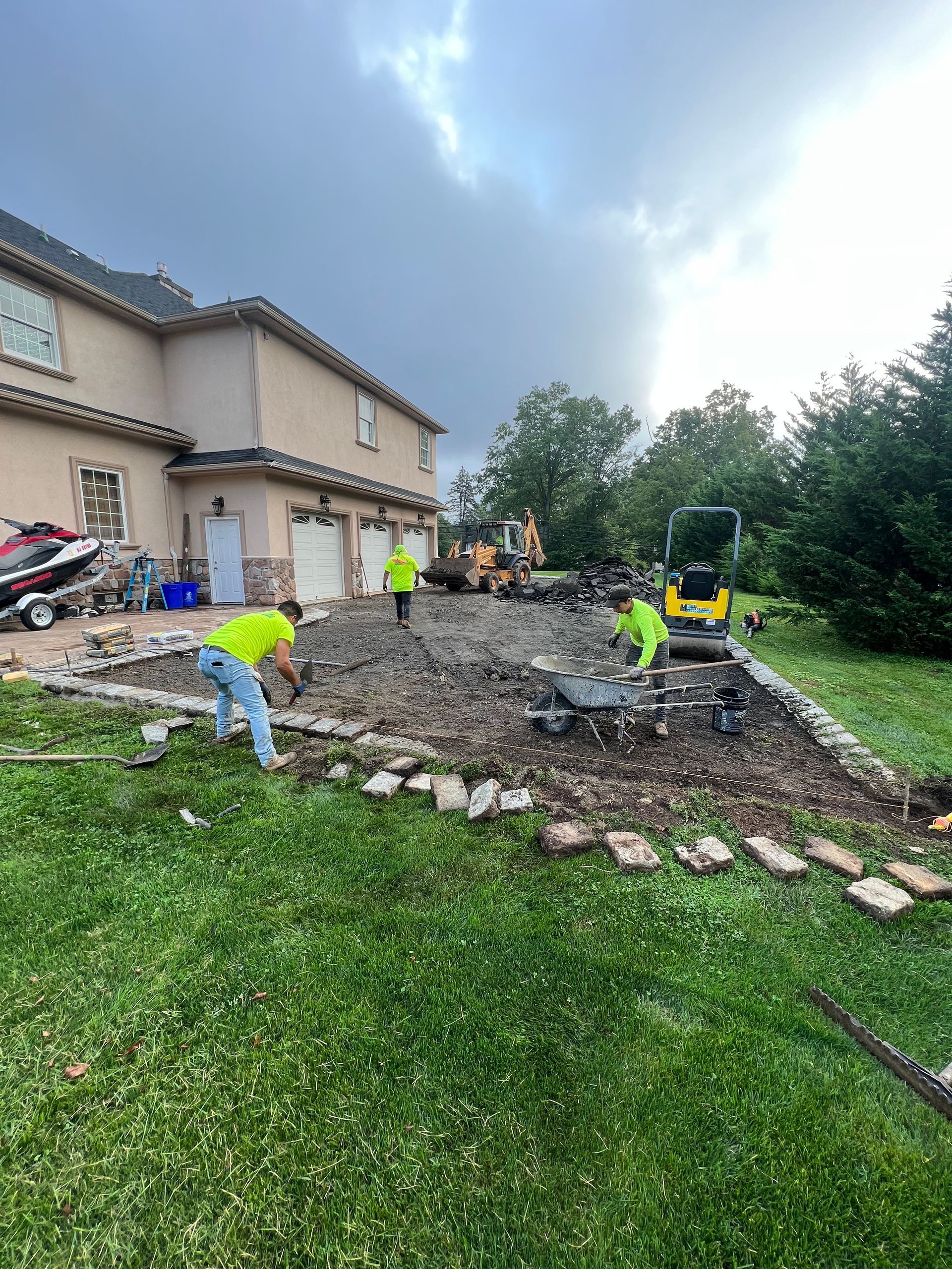 A group of men are working on a driveway in front of a house.
