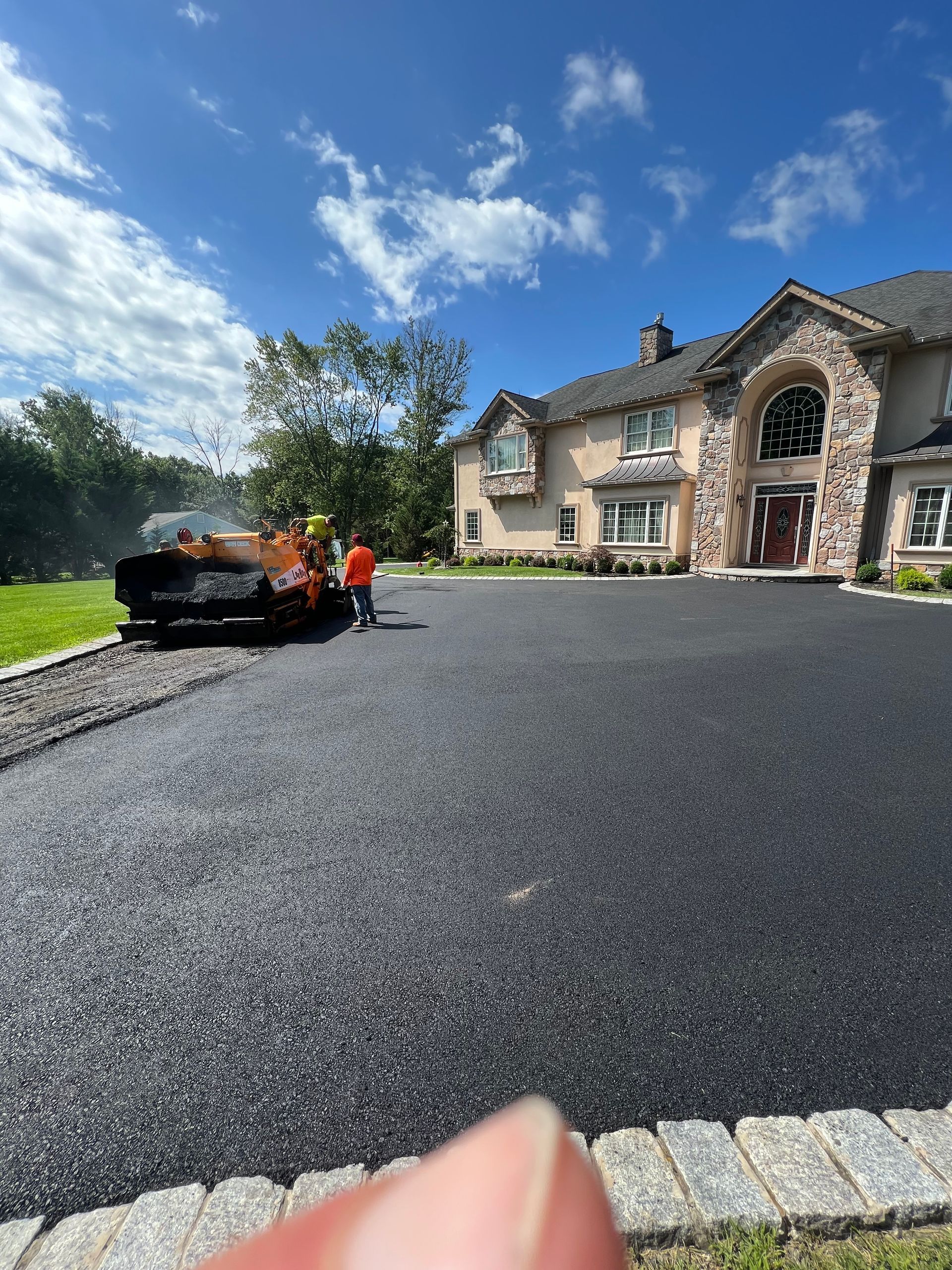 A large house with a large driveway being paved in front of it.
