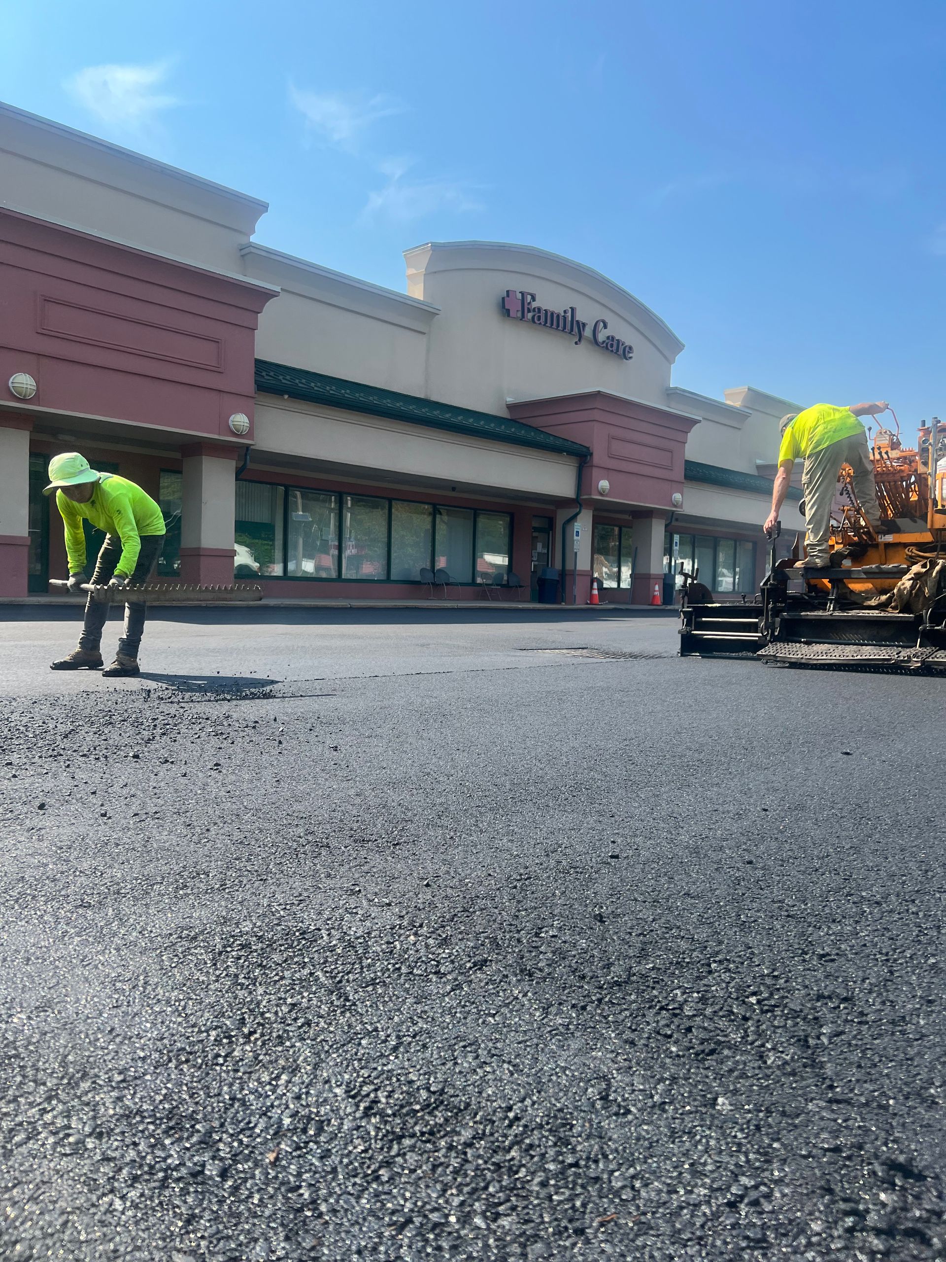 A man is laying asphalt in front of a building.