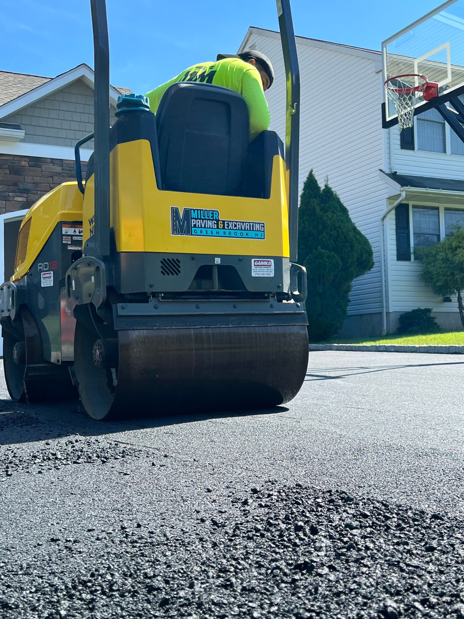 A man is working on a road with a machine that says 'asphalt' on it