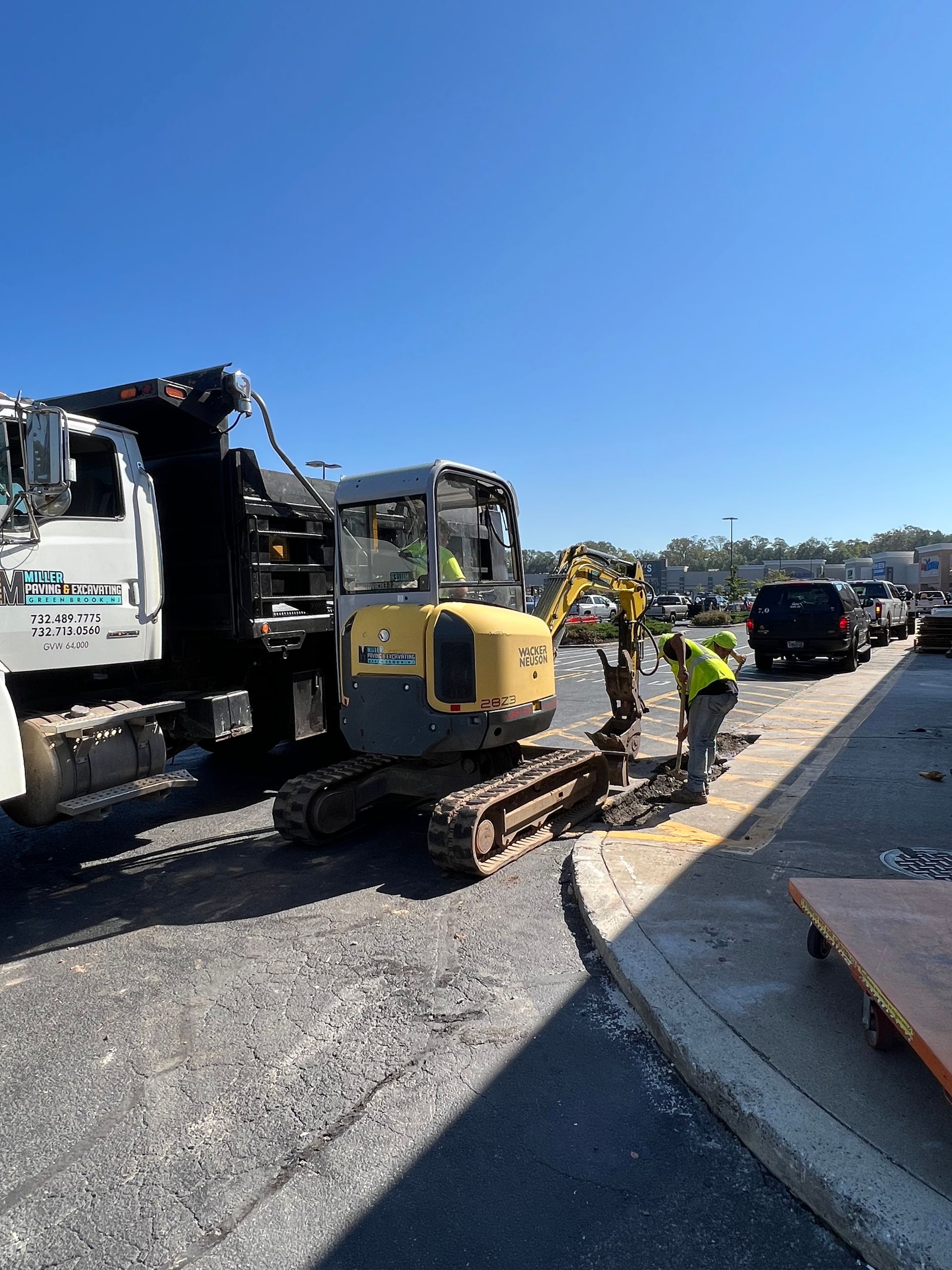 A yellow excavator is parked next to a dump truck.