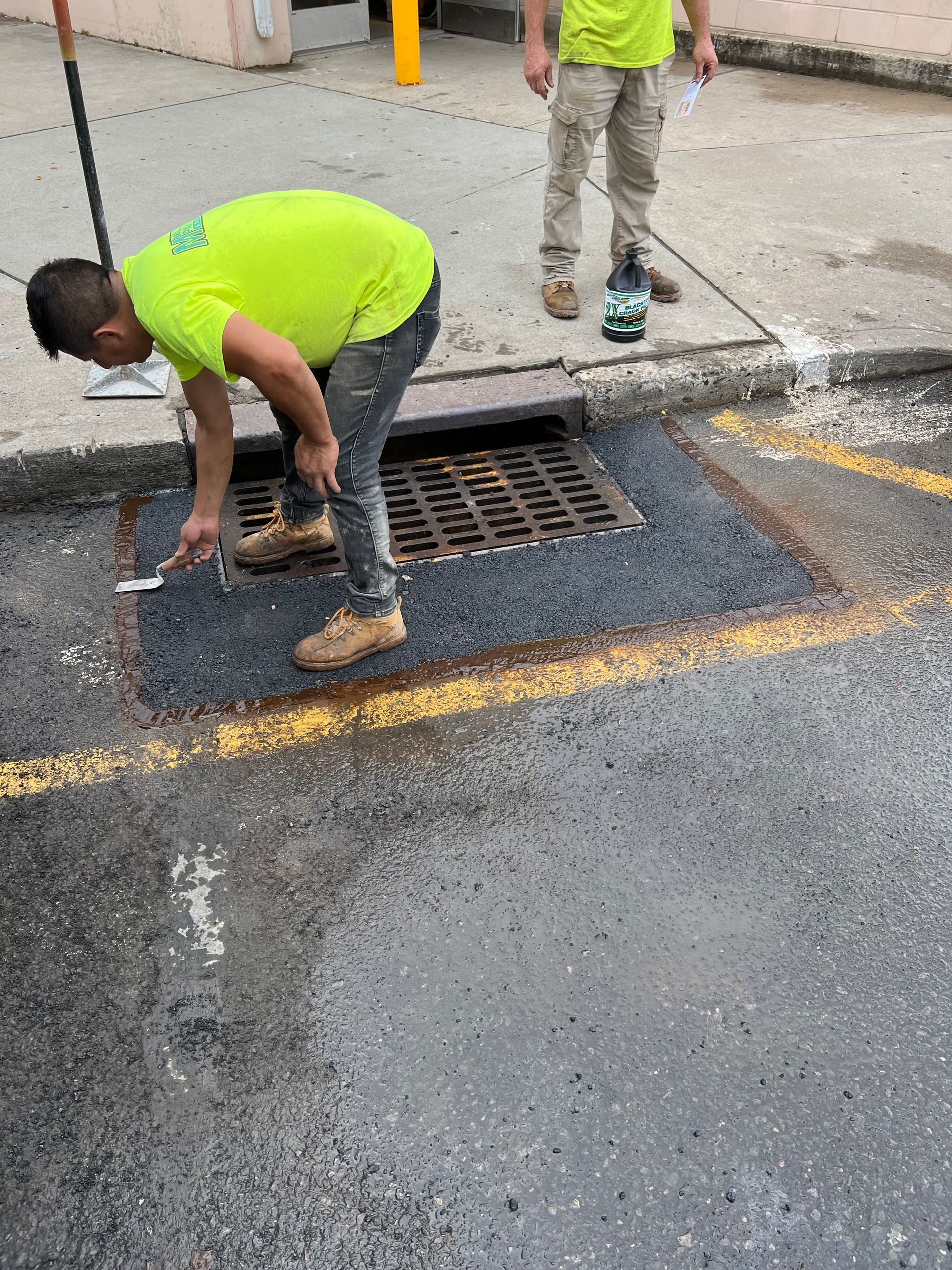 A man is working on a manhole cover on the side of the road.