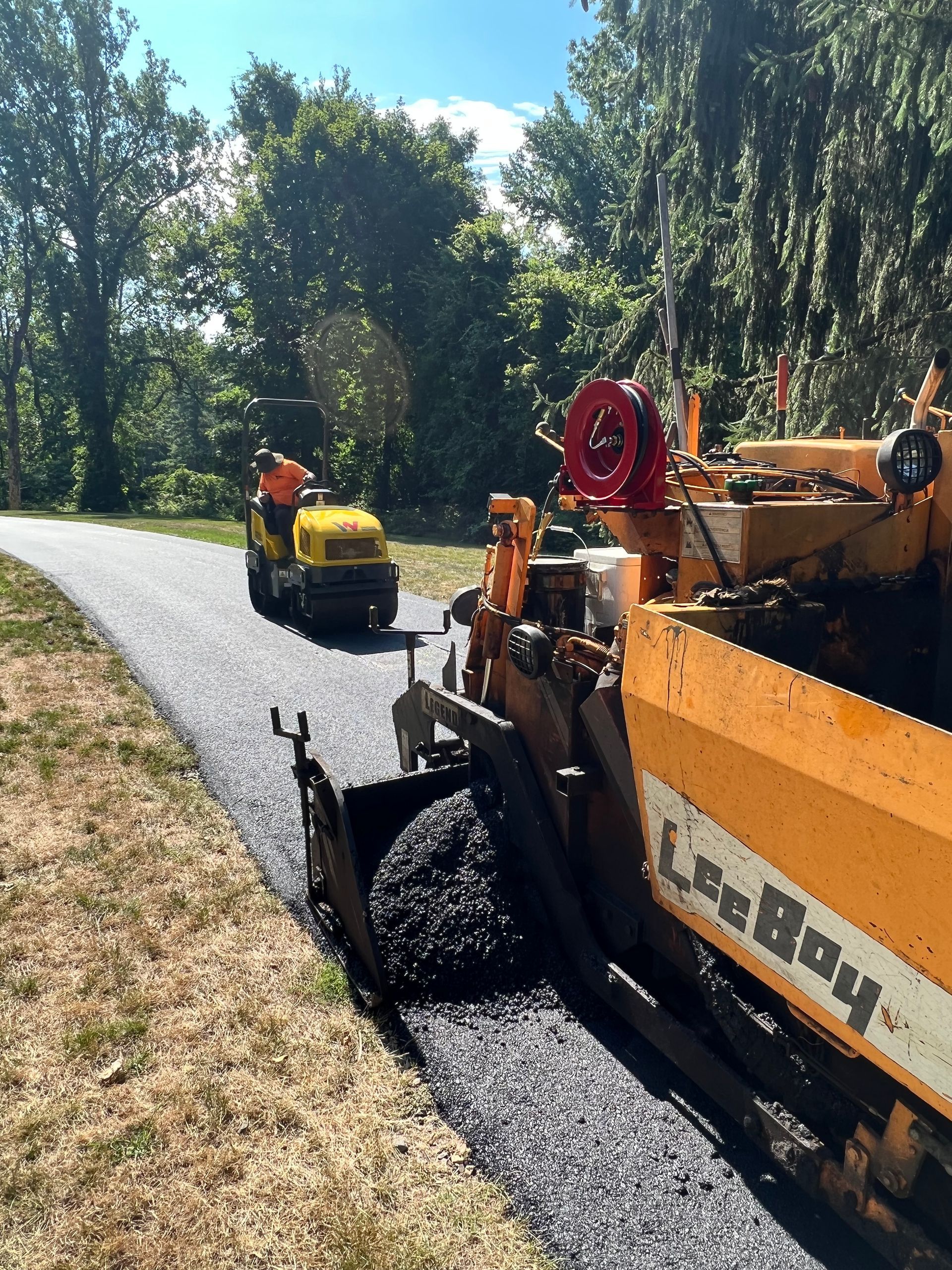 A man is driving a yellow tractor down a road.