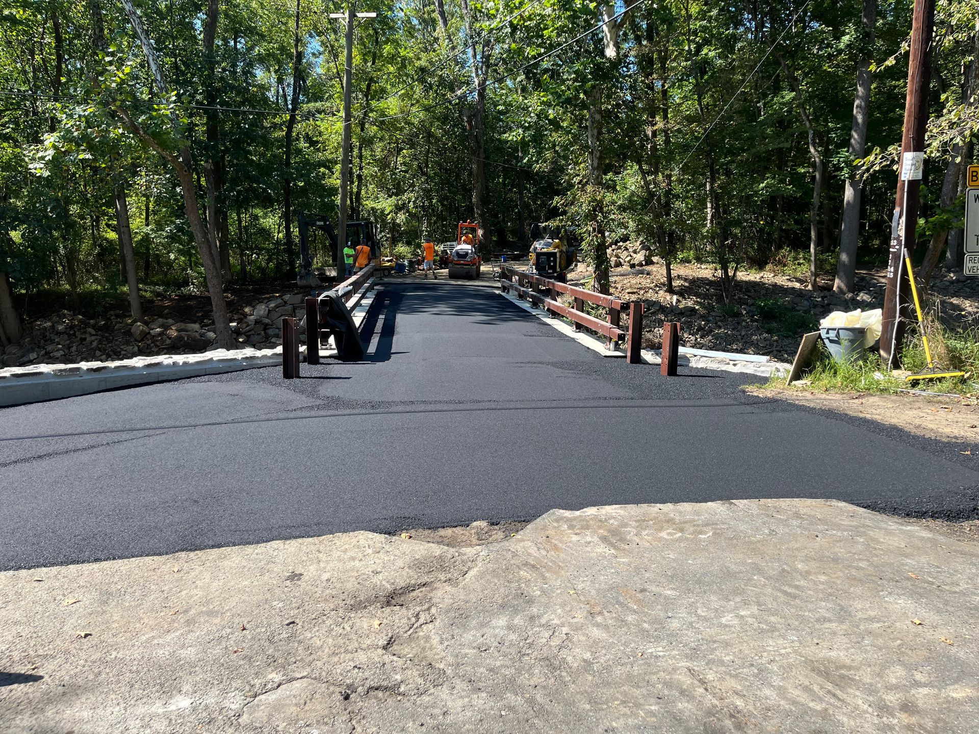 A newly paved road is being built in the woods.