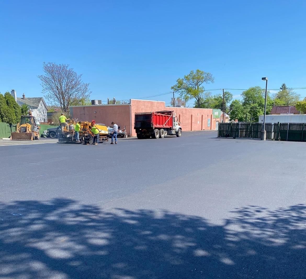 A group of people are standing in a parking lot next to a dump truck.