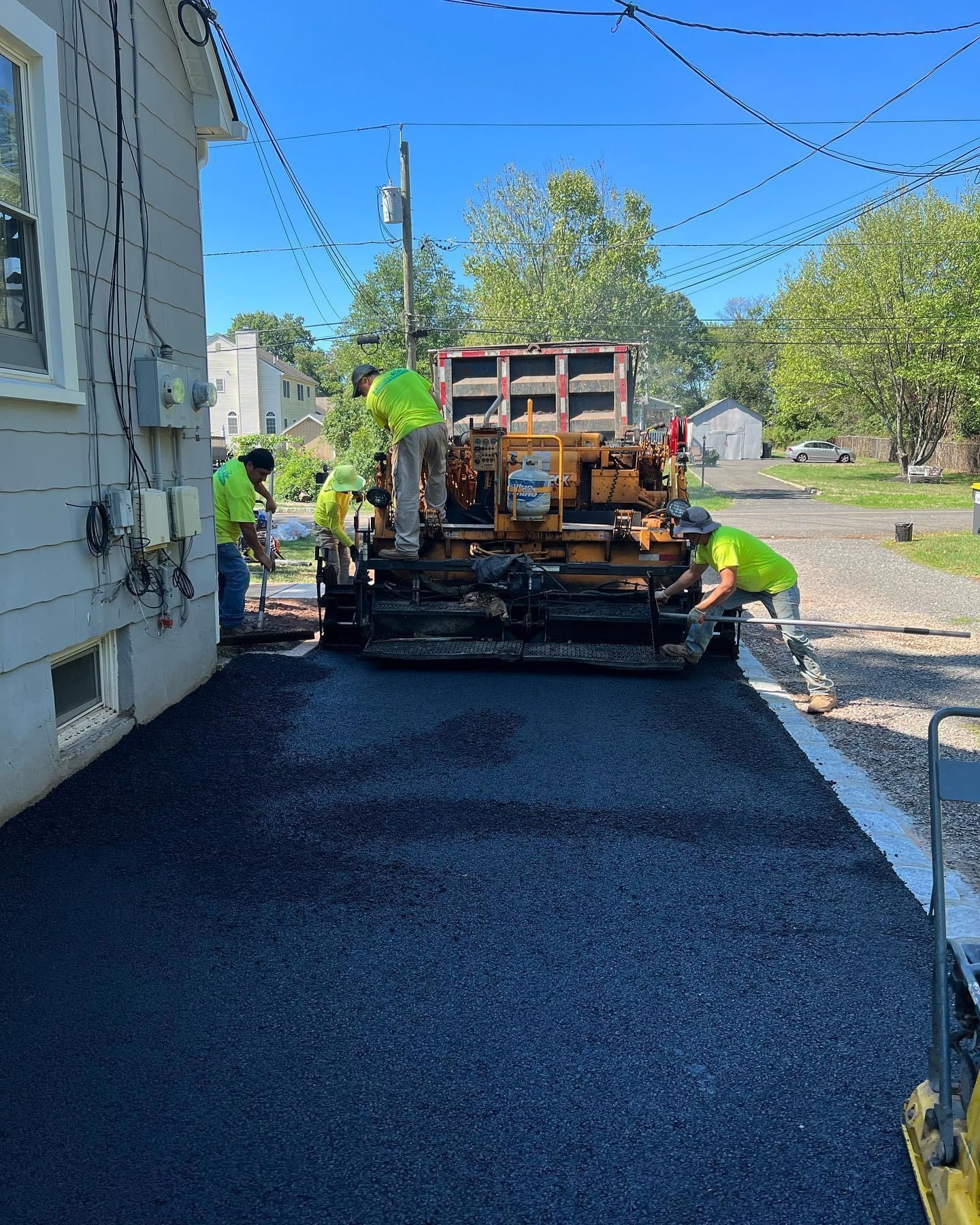 A group of men are working on a road next to a house.