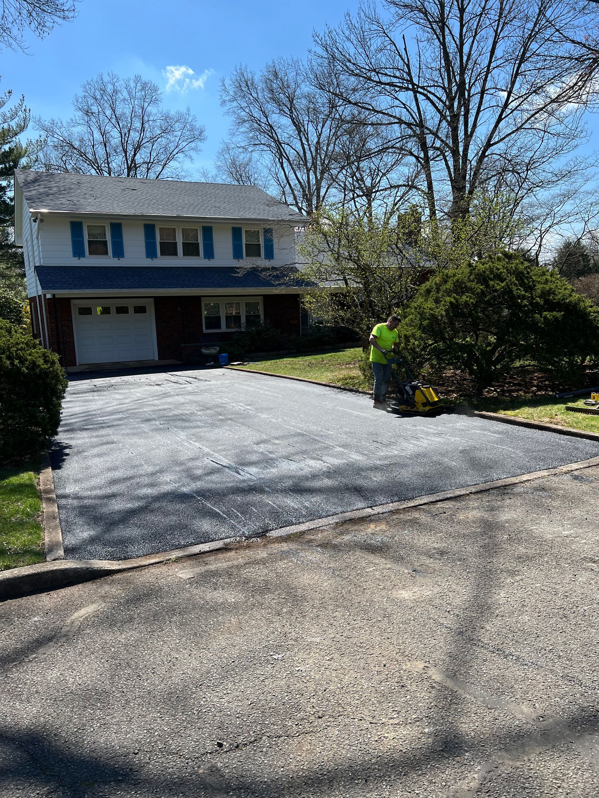 A man is working on a driveway in front of a house.