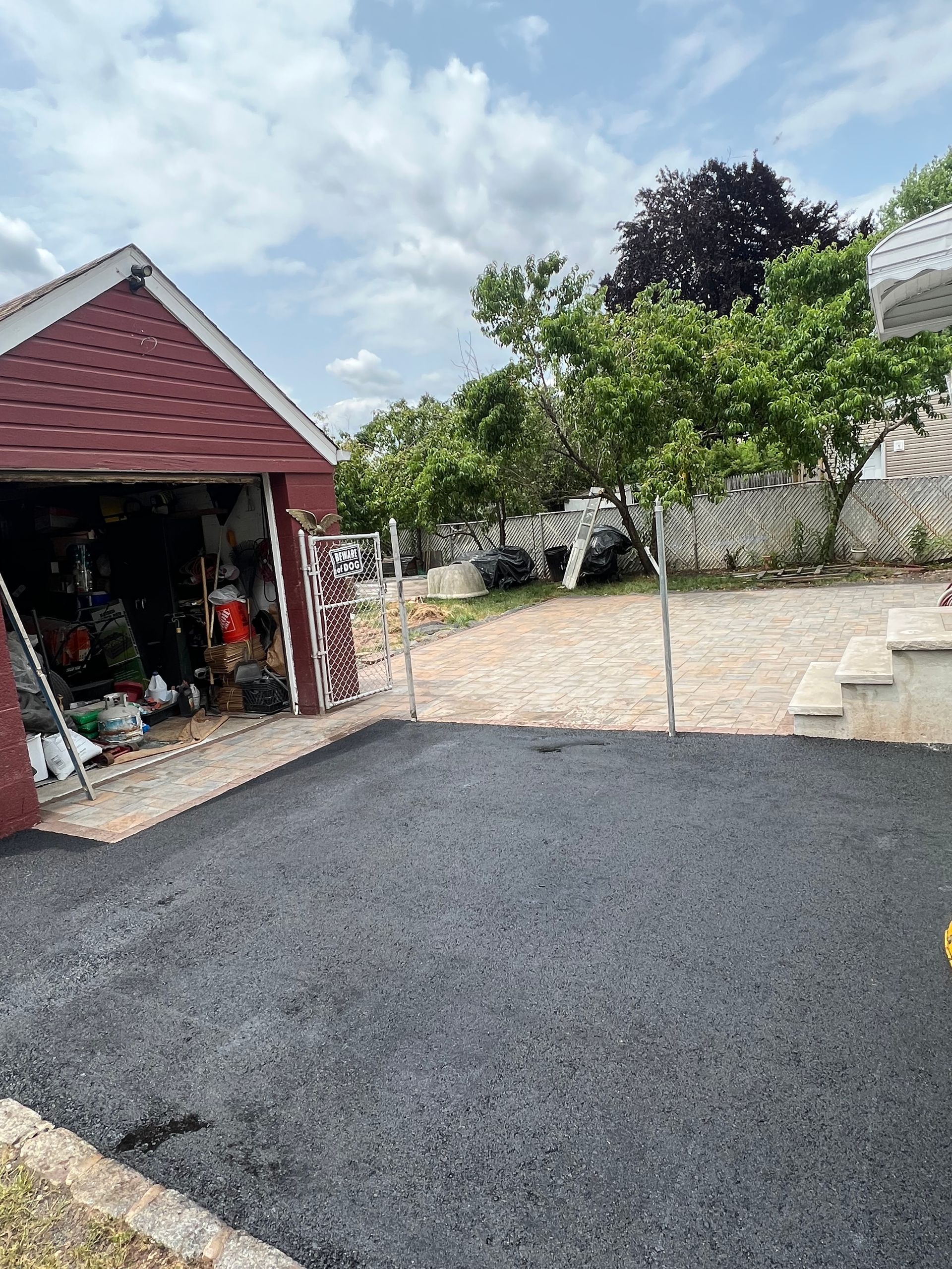 A red garage with a black driveway in front of it.