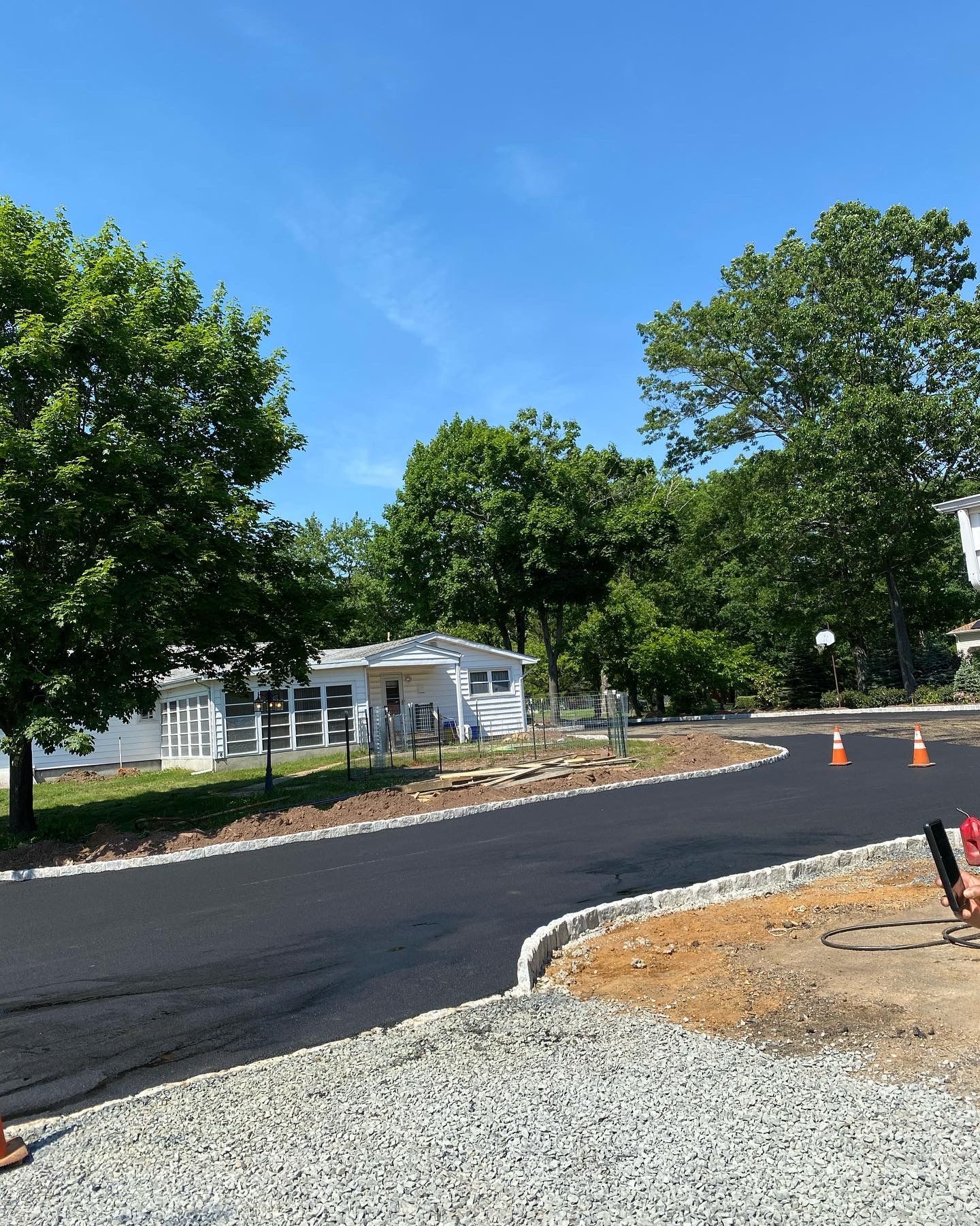A road with a house in the background and trees on the side