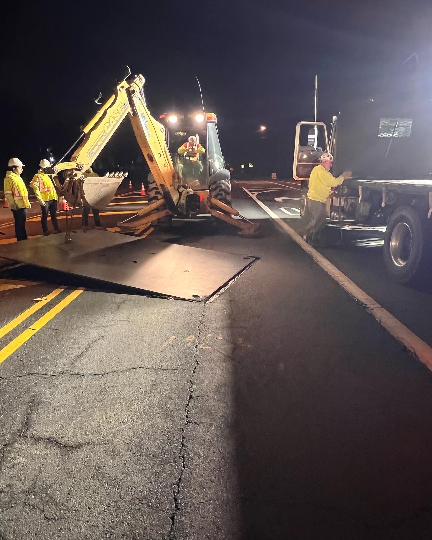 A group of construction workers are working on a road at night