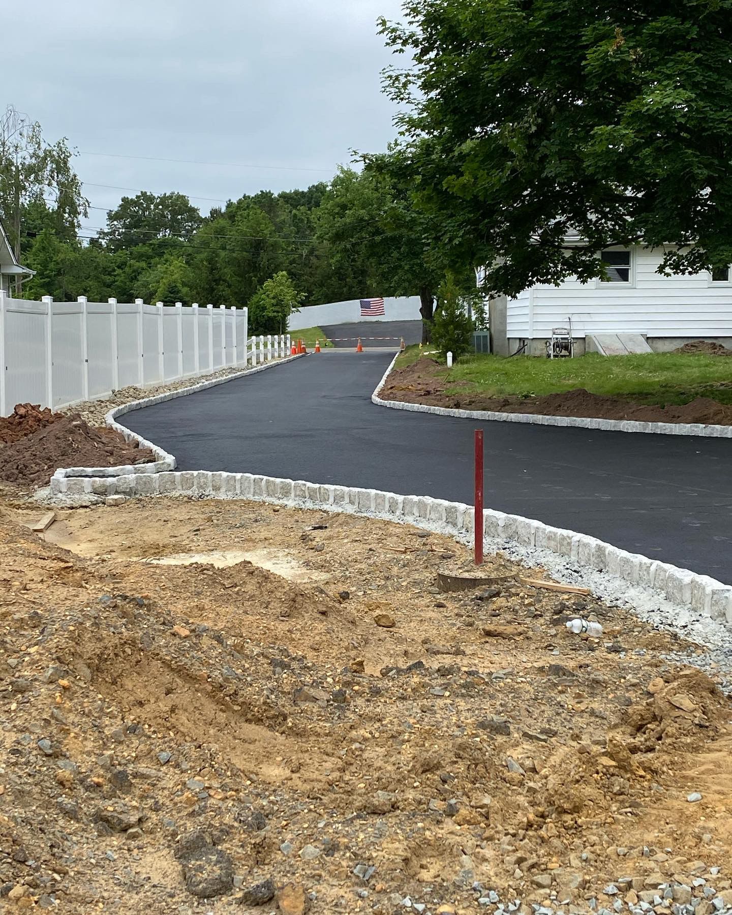 A dirt road with a white fence on the side of it.